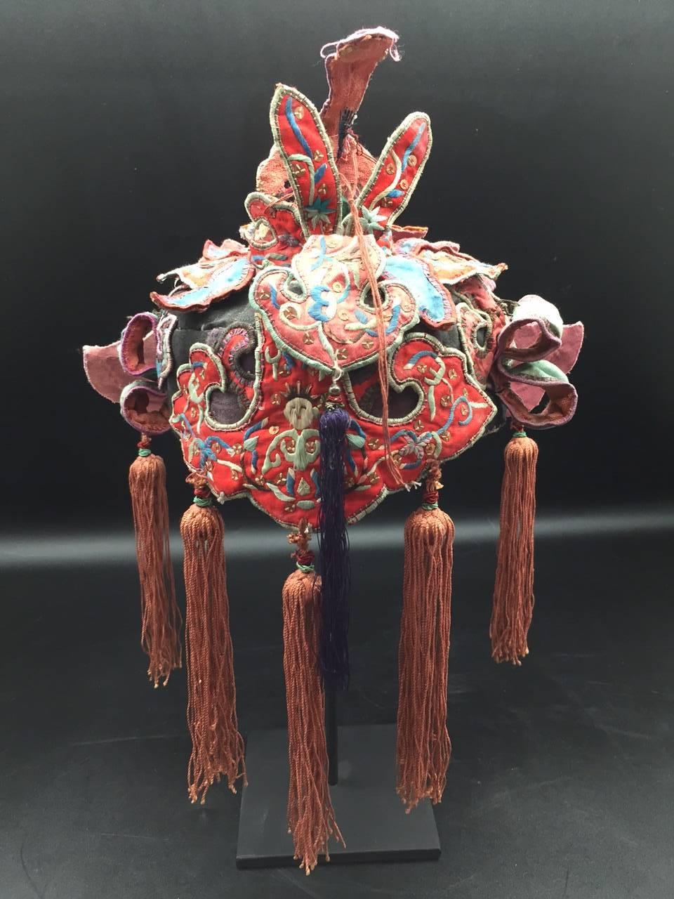 Hand embroidered silk Miao Minority tribe child's headdress with sequins and tassels from the early 20th century on a custom black painted metal mount.