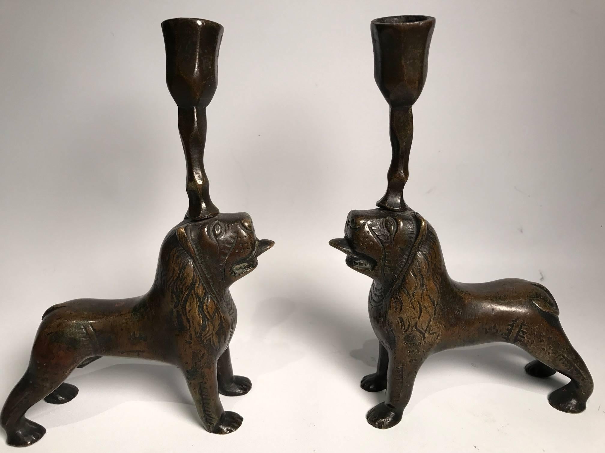 A pair of continental 19th century beautifully patinated bronze lion candlesticks, stylistically in the form of architectural pillar holders know as stylobates, typically seen in the Romanesque cathedrals of Italy, such as Saint Alessandro in