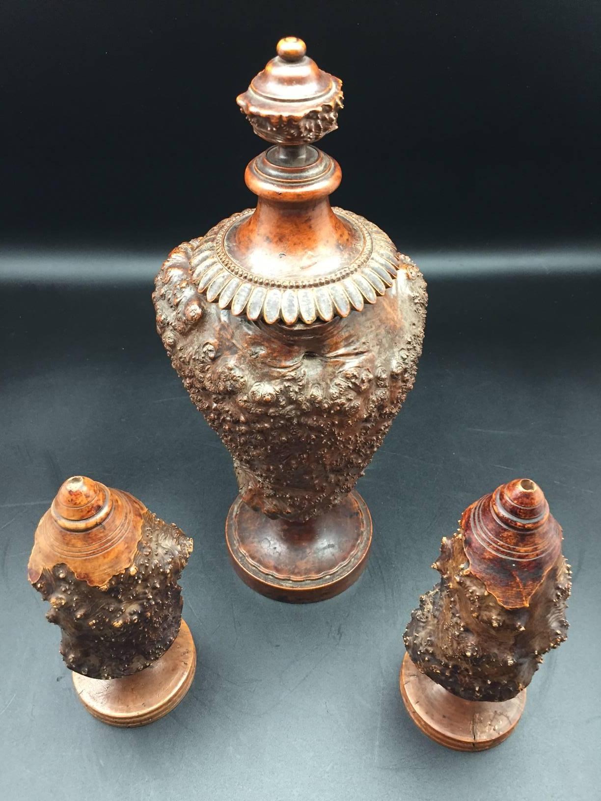 Burr or burl wood 19th century European garniture set of three turned jars. The larger of the three has a turned burl wood finial lid and the other two have turned wooden bases and a hole at the top indicating a possible use as a condiment set.