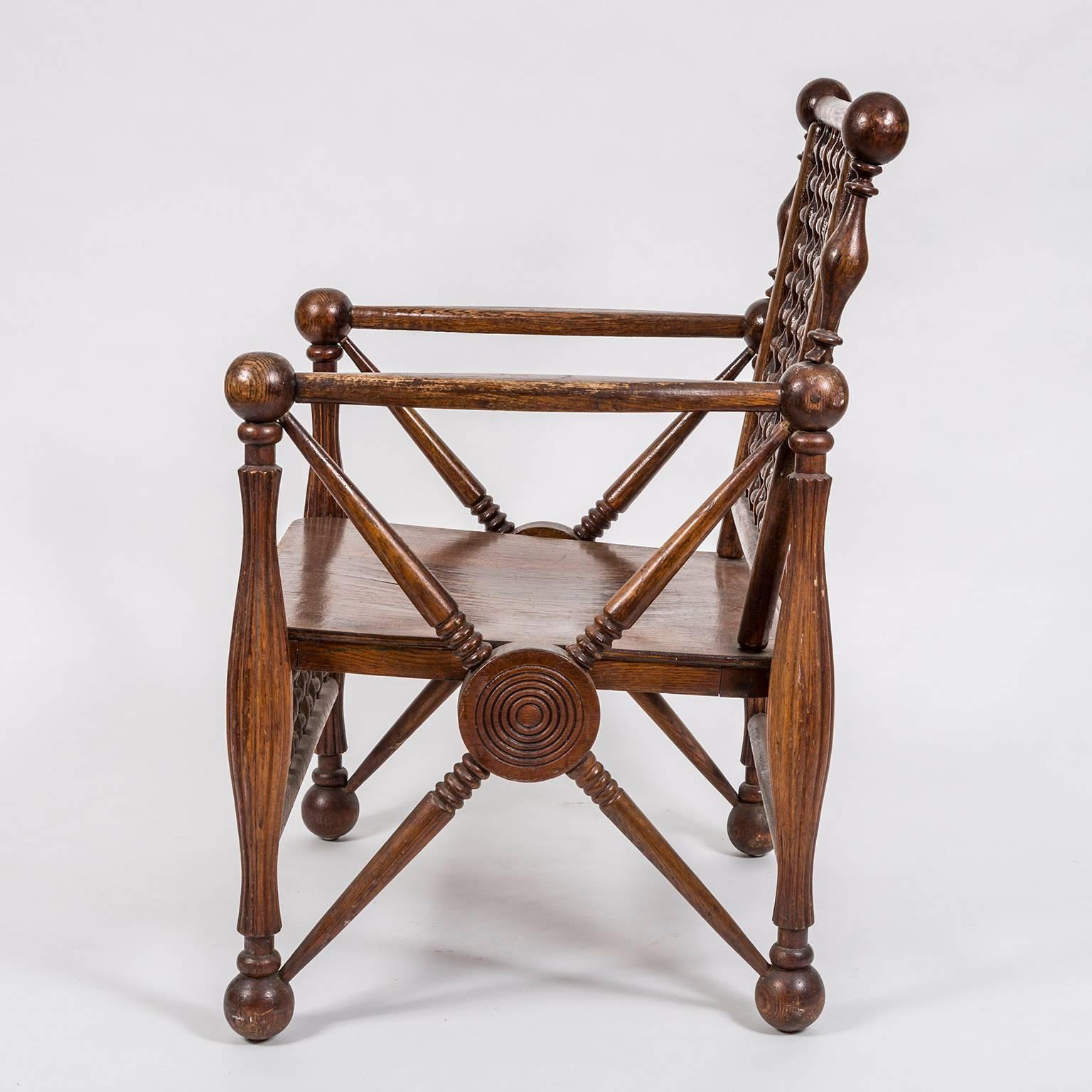 Arts and Crafts period oak lattice fretwork armchair. Probably made in the United States at the beginning of the 20th century, this rare and unusual armchair has the typical geometric form of an Arts and Crafts style armchair but with turned posts