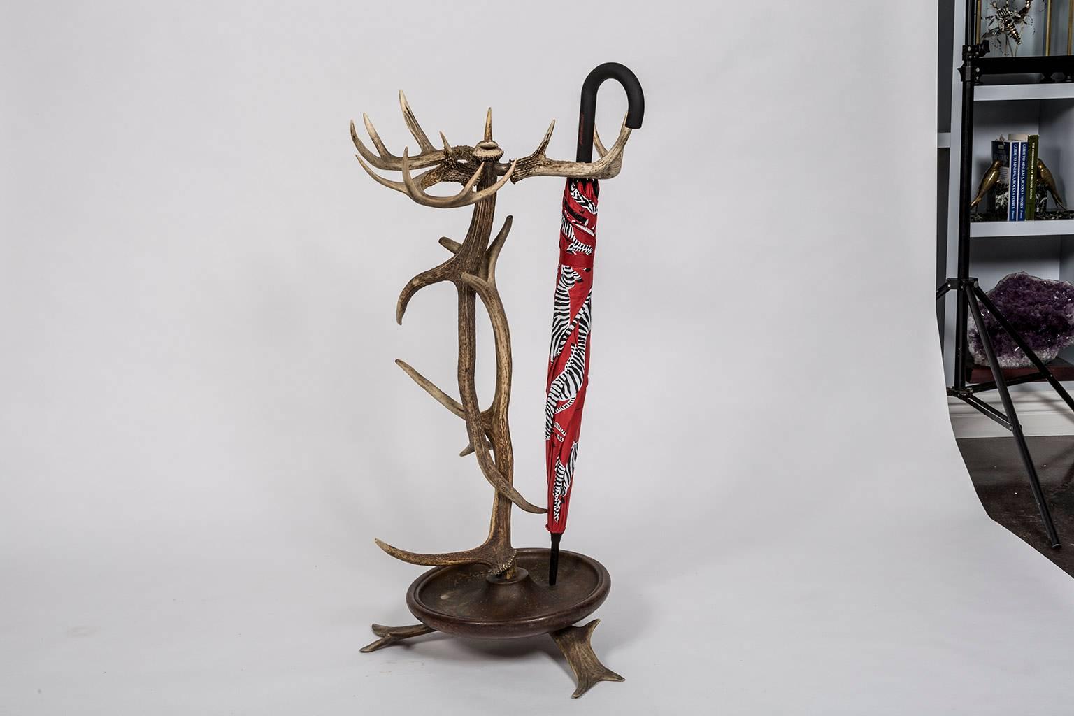 Black Forest style Antler umbrella stand from a 1920s Adirondack Great Camp. The antlers are sturdily affixed to a metal lined wooden drip tray supported by three splayed antlers. This beautiful sculptural item from Mother Nature is not only