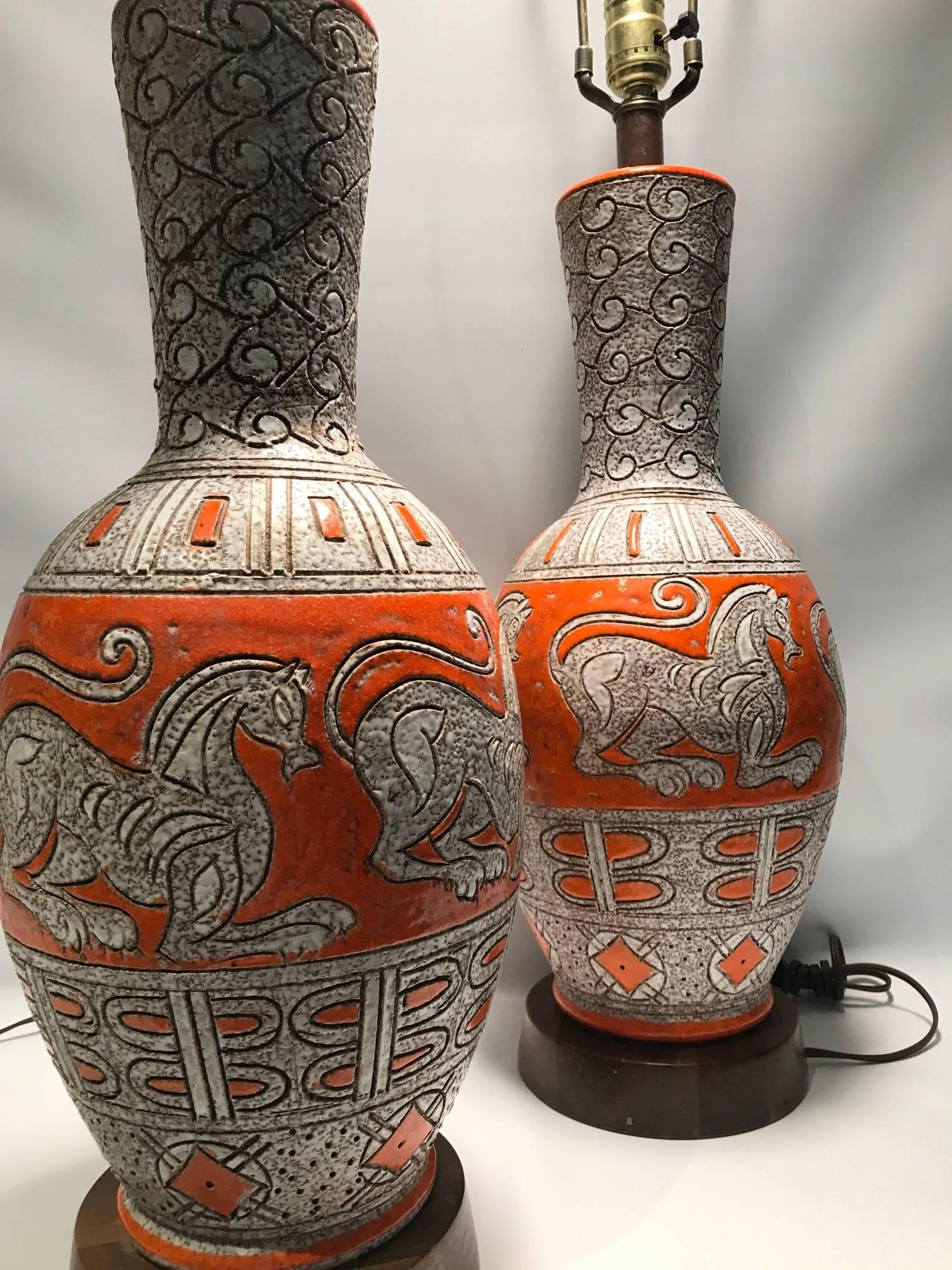 Pair of Mid-Century Italian orange and dappled light brown and grey ground glazed ceramic lamps with incised chimera mythological animal like decoration and abstract motifs, each on a turned wooden base. Electrified for the US. Harp and finial and