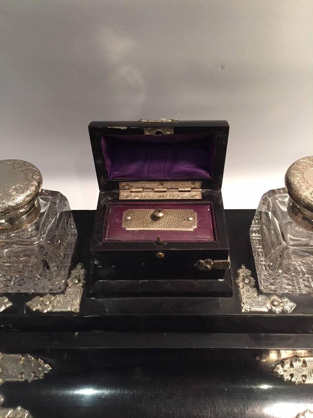 Crystal, sterling silver, and ebonized wood inkwell desk set by George Bedingham, Great Britain, 1870.
The set consists of two crystal and sterling-silver-hinged inkwells, a pen holder, and a small chest for metal nibs. Compartment storage is
