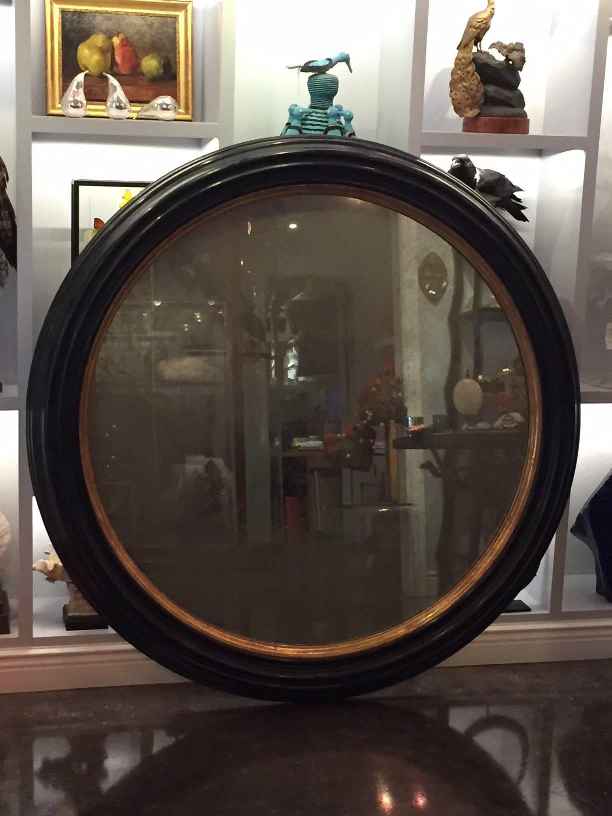 Spectacular and large, this unique piece is a show-stopper for your worthy space. Vintage incredibly large (almost 5 feet in diameter) black painted and giltwood framed mirror. Width of frame is 6