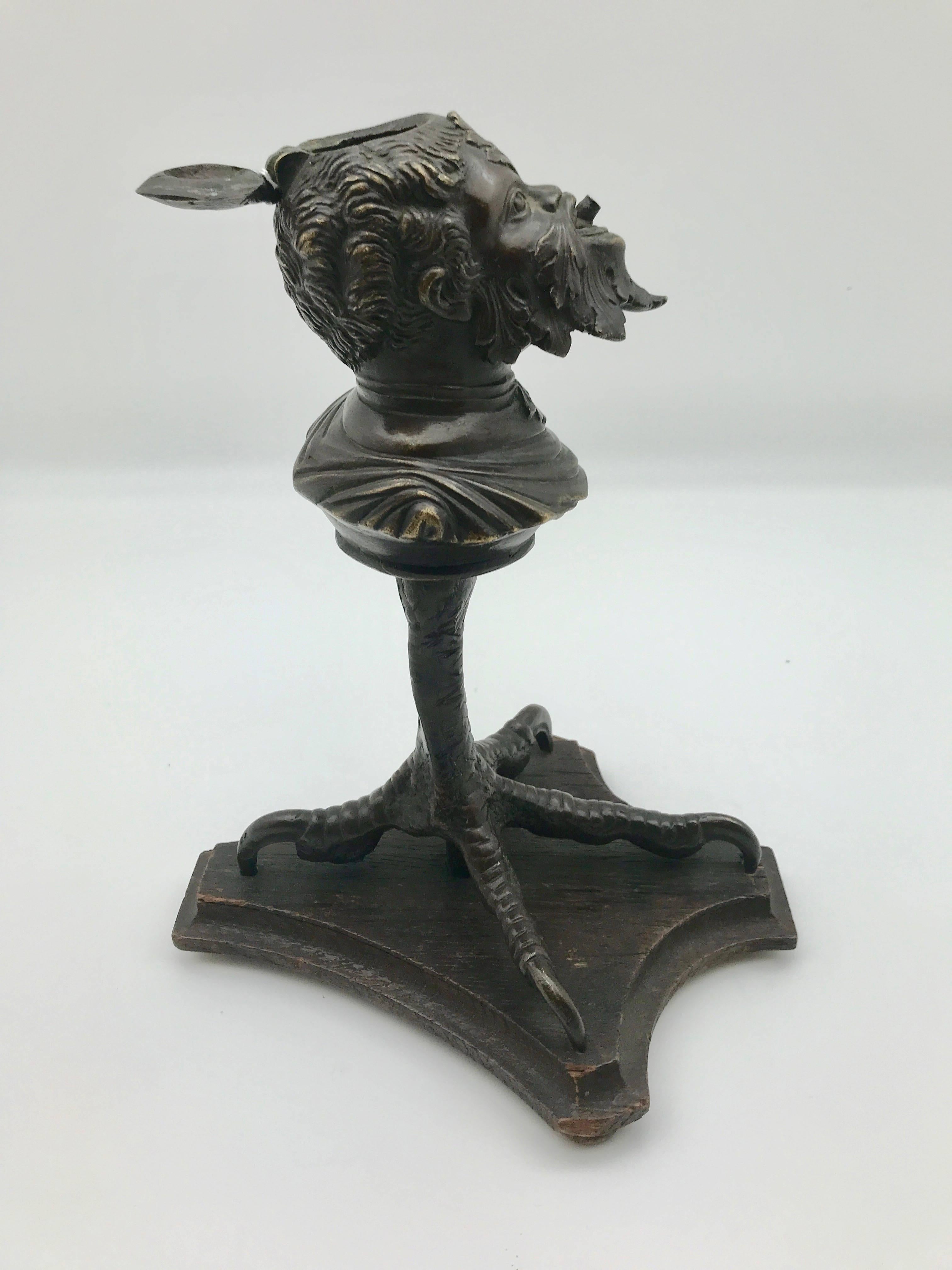 Unique 19th century Continental bronze tobacco cigar lighter. The cast head, smoking a cigar, is mounted on a bird's claw on top of a wooden base. The reservoir, once filled with oil through a hinged lid at the top, can be used to use to light your