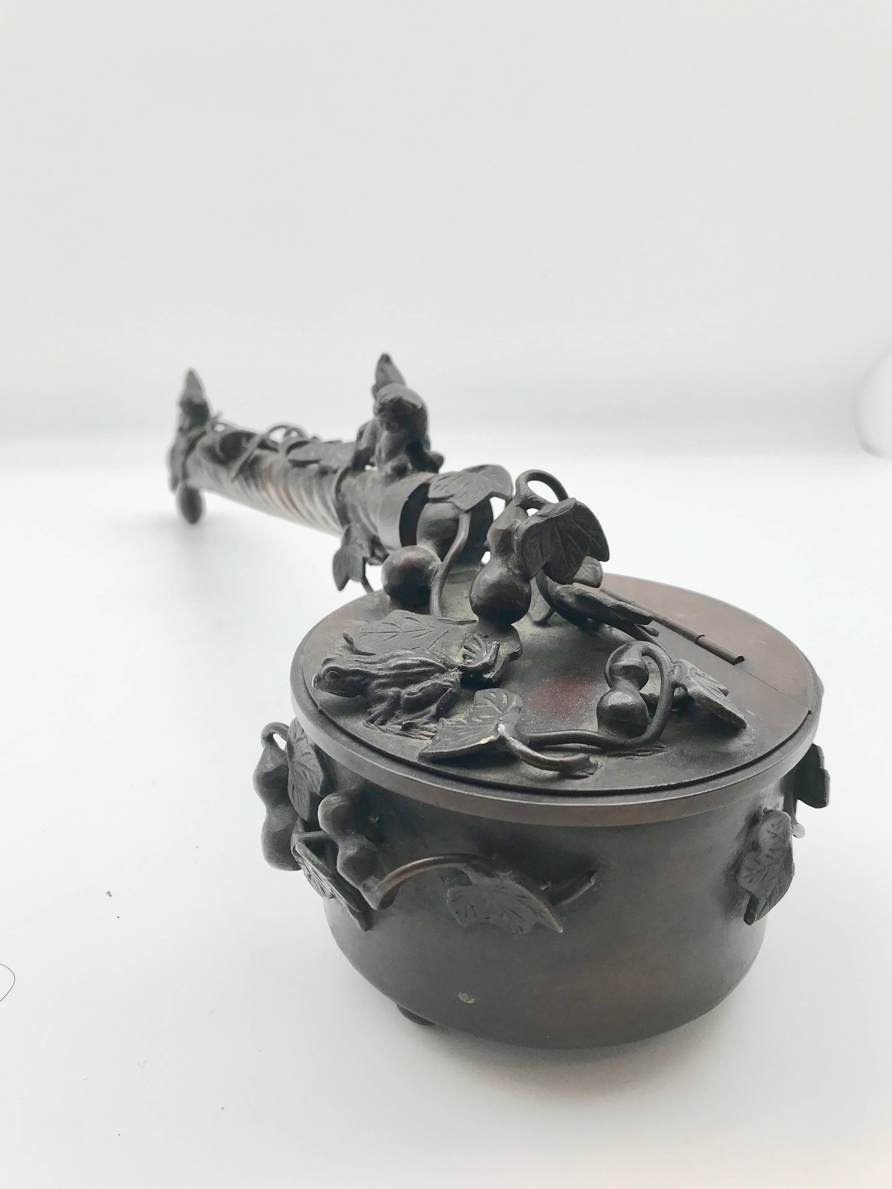 Antique Japanese Yatate bronze calligraphy box. Shishi dogs, leaves, vines, and gourds can be found on the long handle that ends with a hook to hang from a scholar's belt. The decorated lid features a charming frog as well.