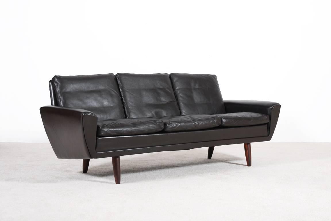 Elegant three-seat vintage sofa.
Structure in solid wood trimmed in dark brown leather, tapered legs in rosewood, cushions filled with feathers.
Danish manufacturing around 1960.