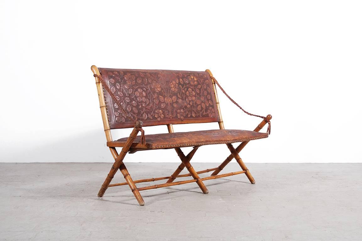 Unusual and unique folding bench, France, 1900.
Oak wood structure imitating the bamboo. And extremely Fine tooled leather work. Laced leather armrests.

Very good condition, can be used and folded again.