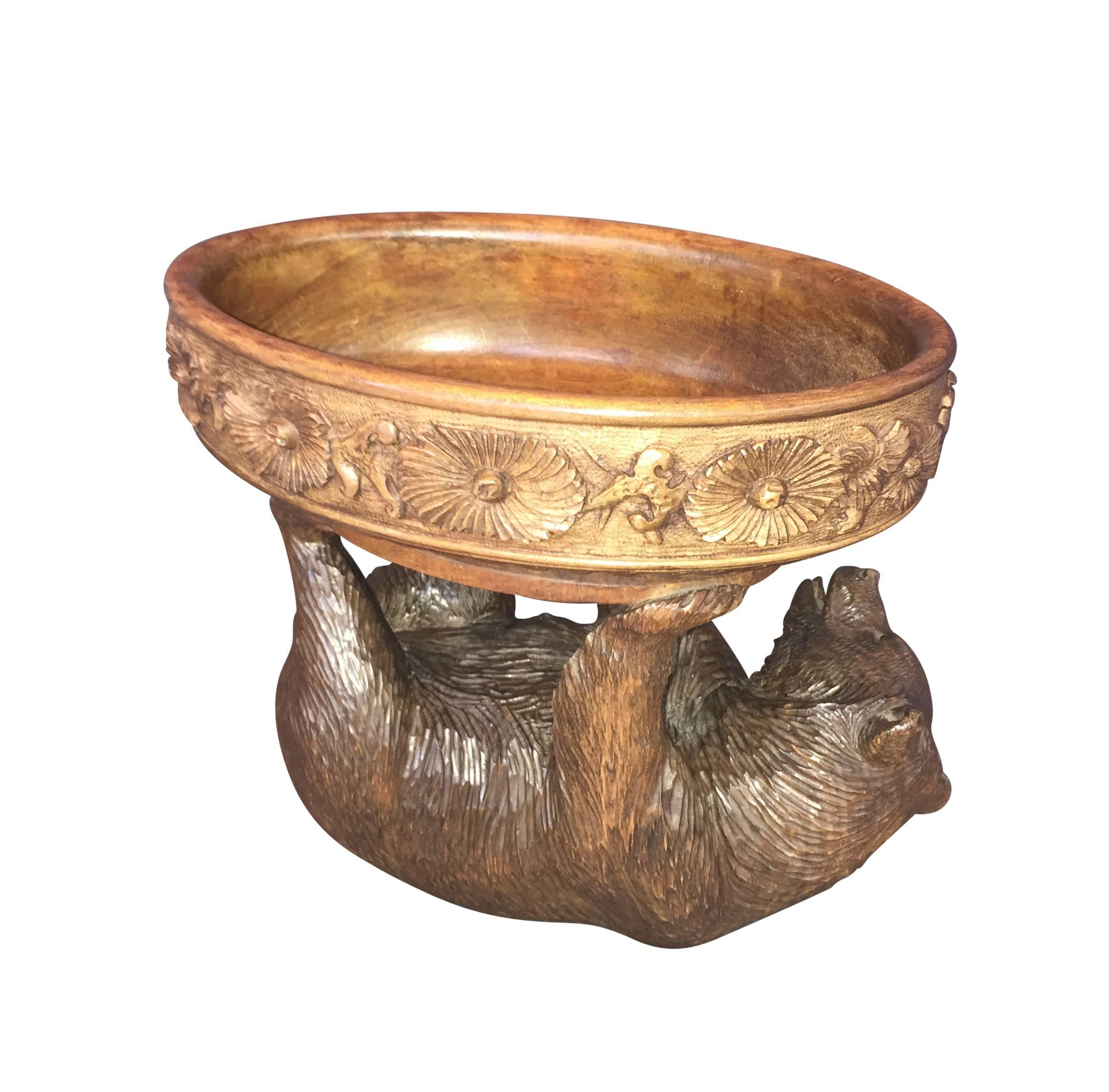 A stunning Swiss Black Forest walnut carving modeled as a bearing lying on its back. The bowl features floral motifs.