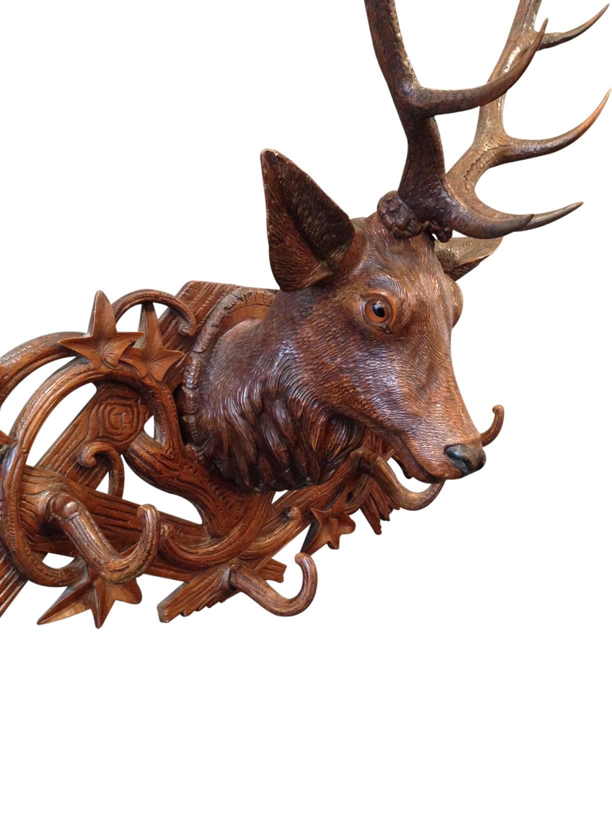 This is a Swiss “Black Forest” carved linden wood stag coat rack. It is very large and very rare. The stag’s head has carved linden wood antlers mounted upon a carved fence style plaque with vines. The overall size, detail and coloring makes this a