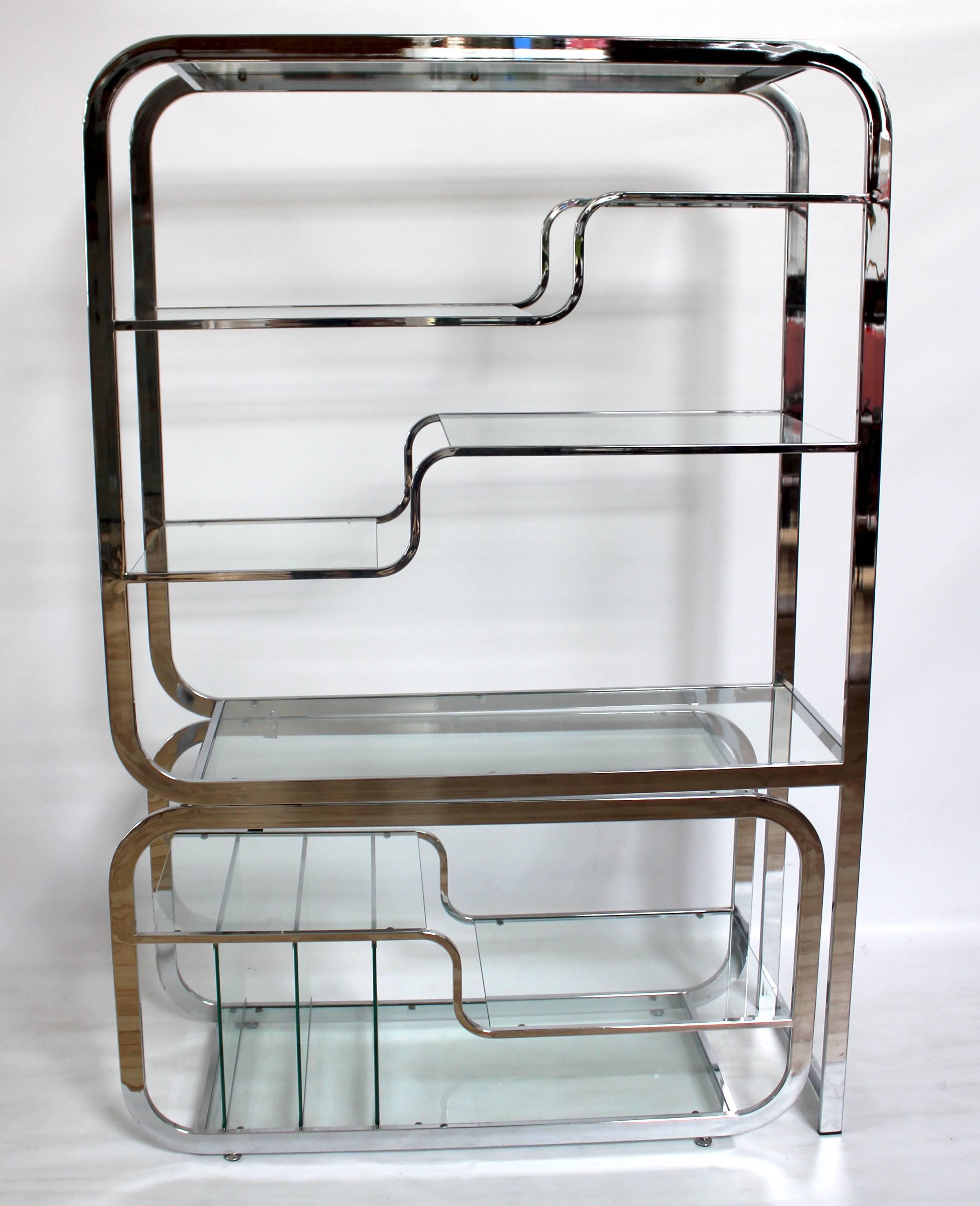 1970s chrome and glass etagere designed by Milo Baughman. The bottom section extends out from the body and features vertical glass record/magazine dividers.