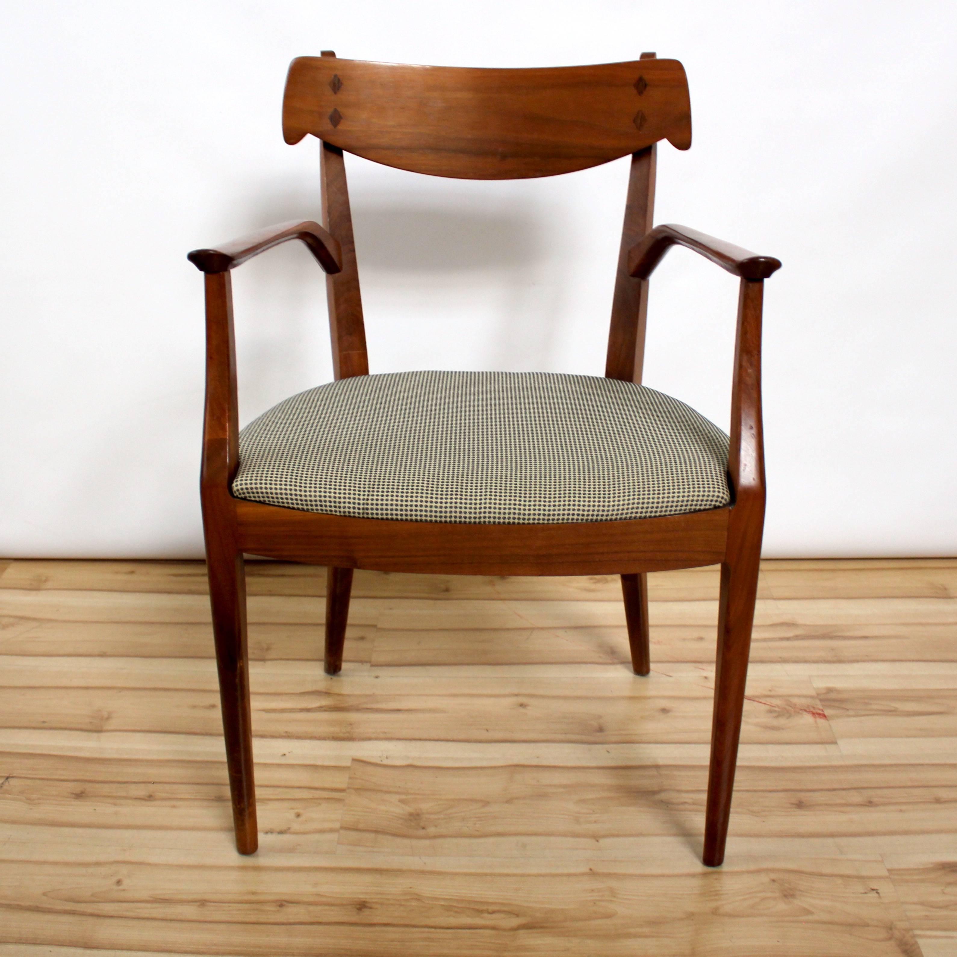 Set of six Mid-Century Modern dining chairs designed by Kipp Stewart and Stewart MacDougall for Drexel Declaration, circa 1960. There are two captain's chairs and four side chairs. Chairs are walnut with rosewood inlay detail, and all chairs have