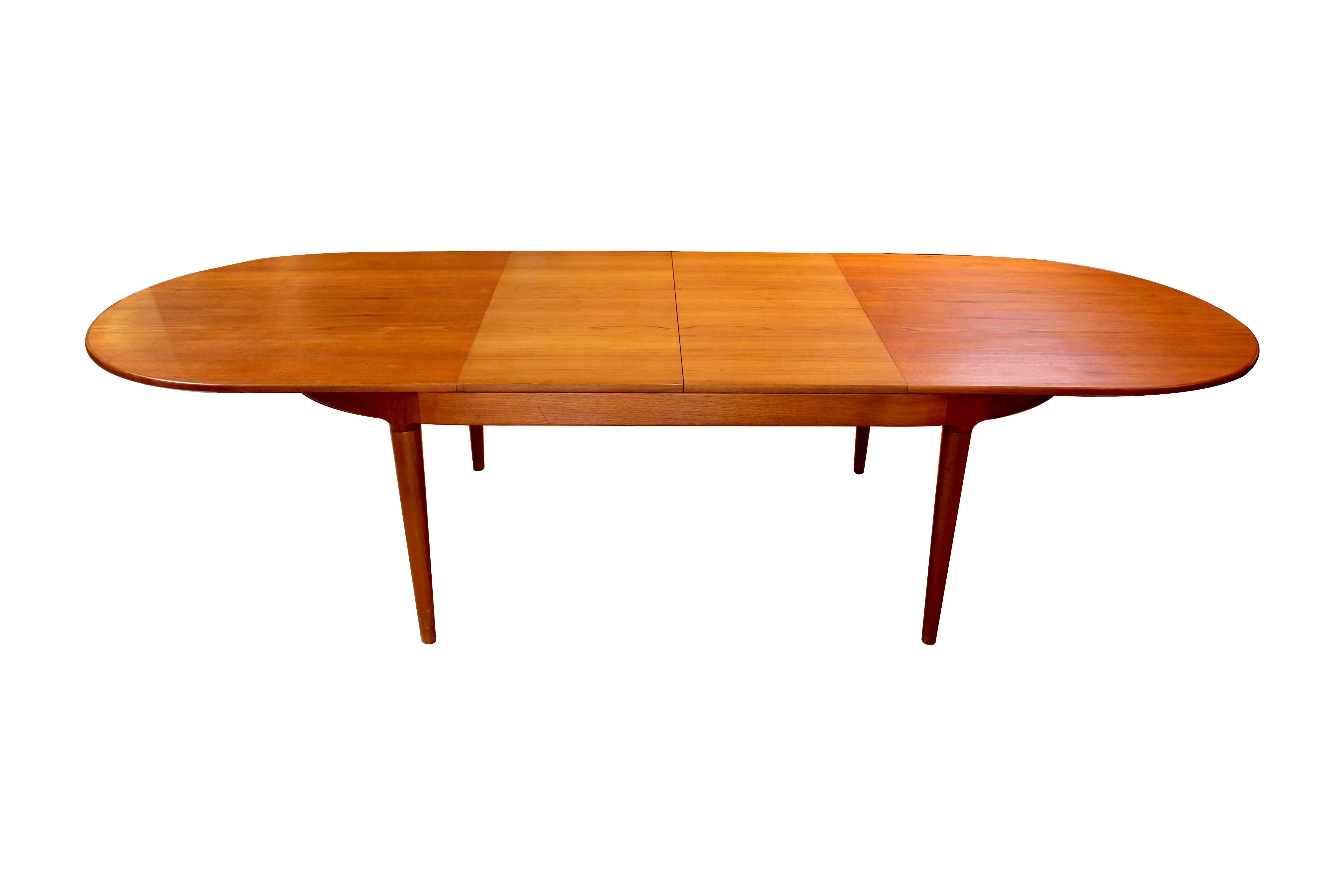 Early 1960s Danish Modern teak dining table with two butterfly leaves, designed by Arne Hovmand-Olsen for Mogens Kold. The leaves store internally; the top slides apart (while the legs stay in place) and the leaves fold out. Without the leaves, the
