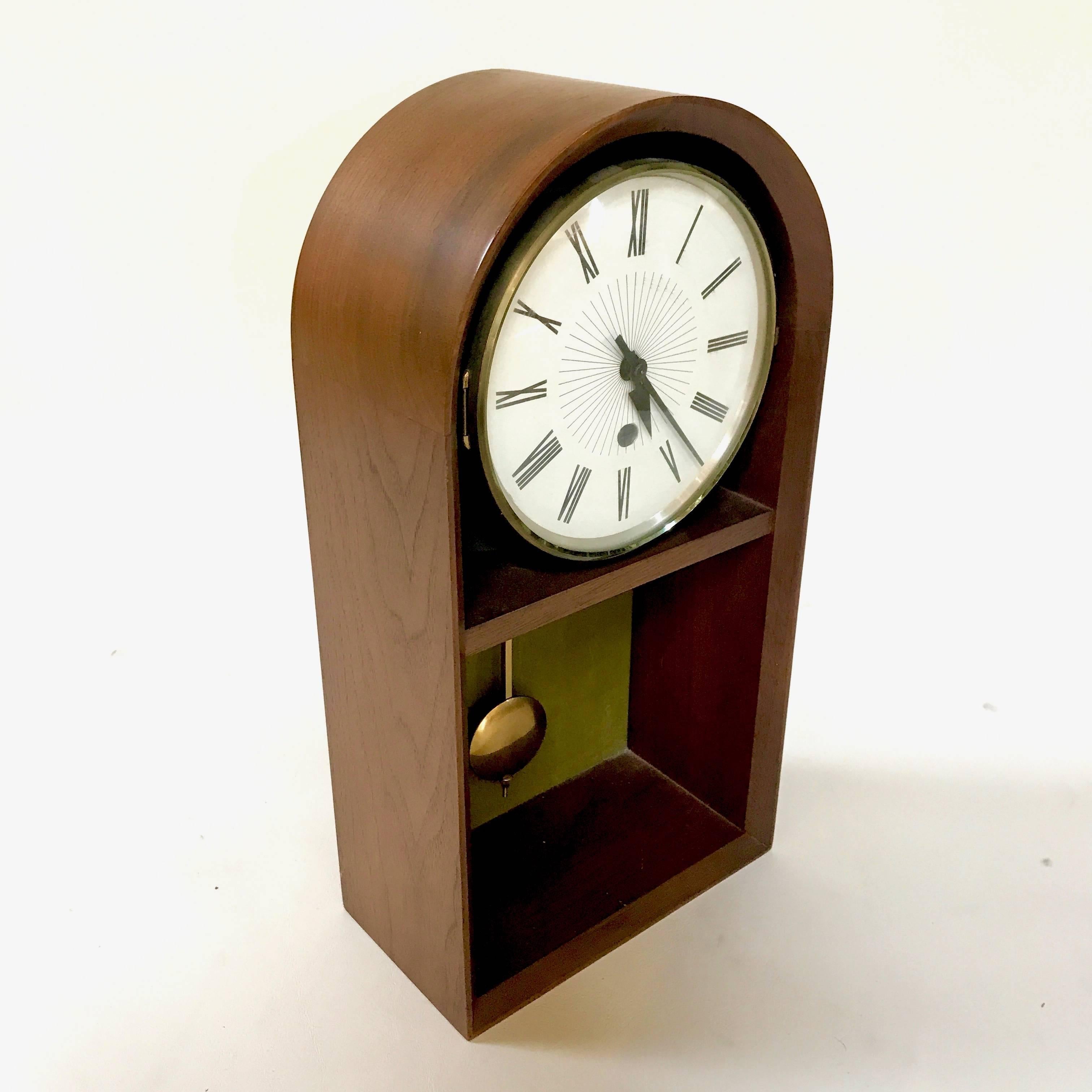 Mid-Century walnut pendulum tabletop pendulum clock by Howard Miller, attributed to Arthur Umanoff. In excellent condition with bubble glass over clock face and original key. Resembles a grandfather clock, with a beautiful walnut case. Eight-day