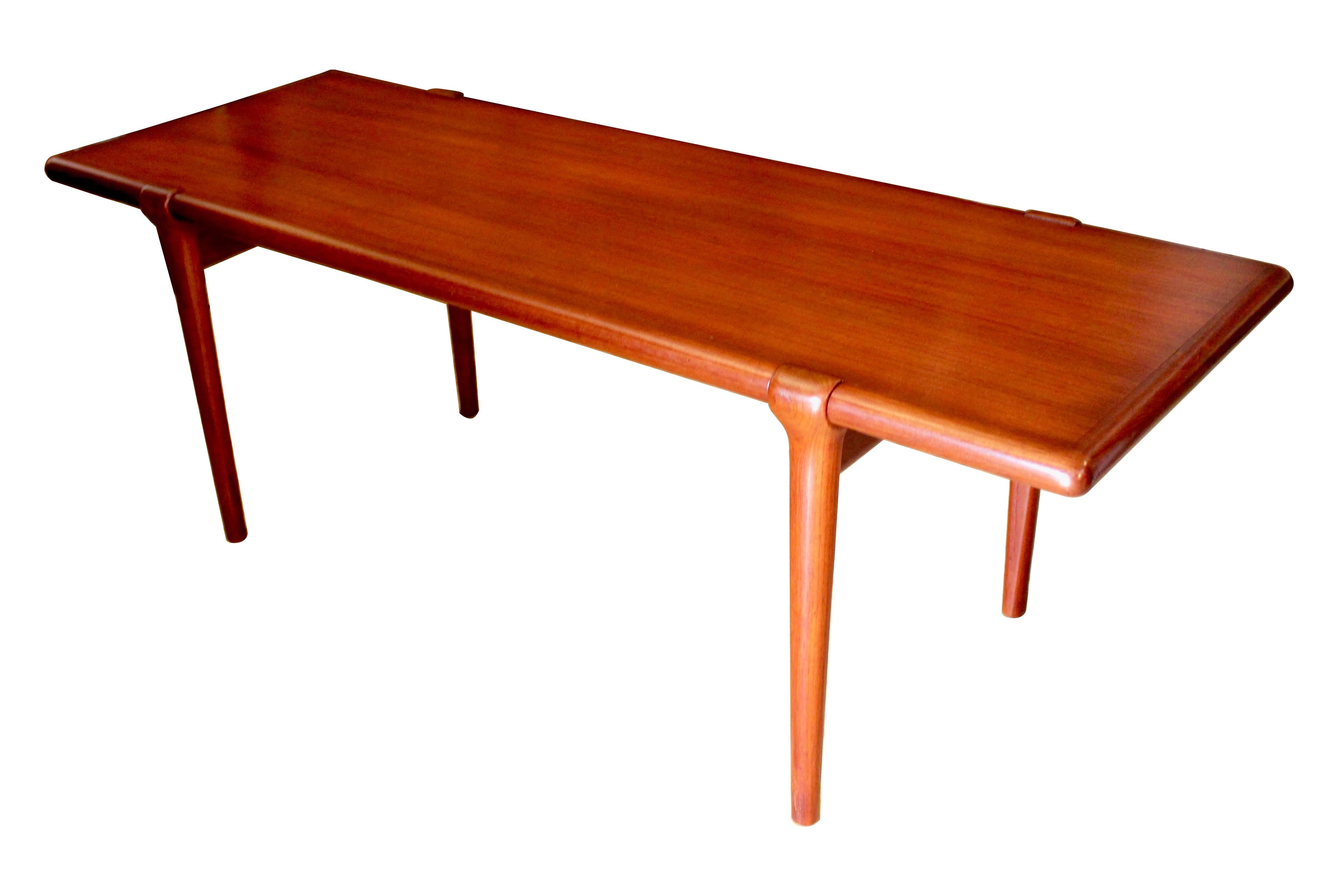 1950s, Danish modern teak coffee table designed by Johannes Andersen for Uldum Møbelfabrik. In excellent condition with no marks or scratches. An early design by Andersen, with a very nice detail in which the legs wrap over the edges of the tabletop.