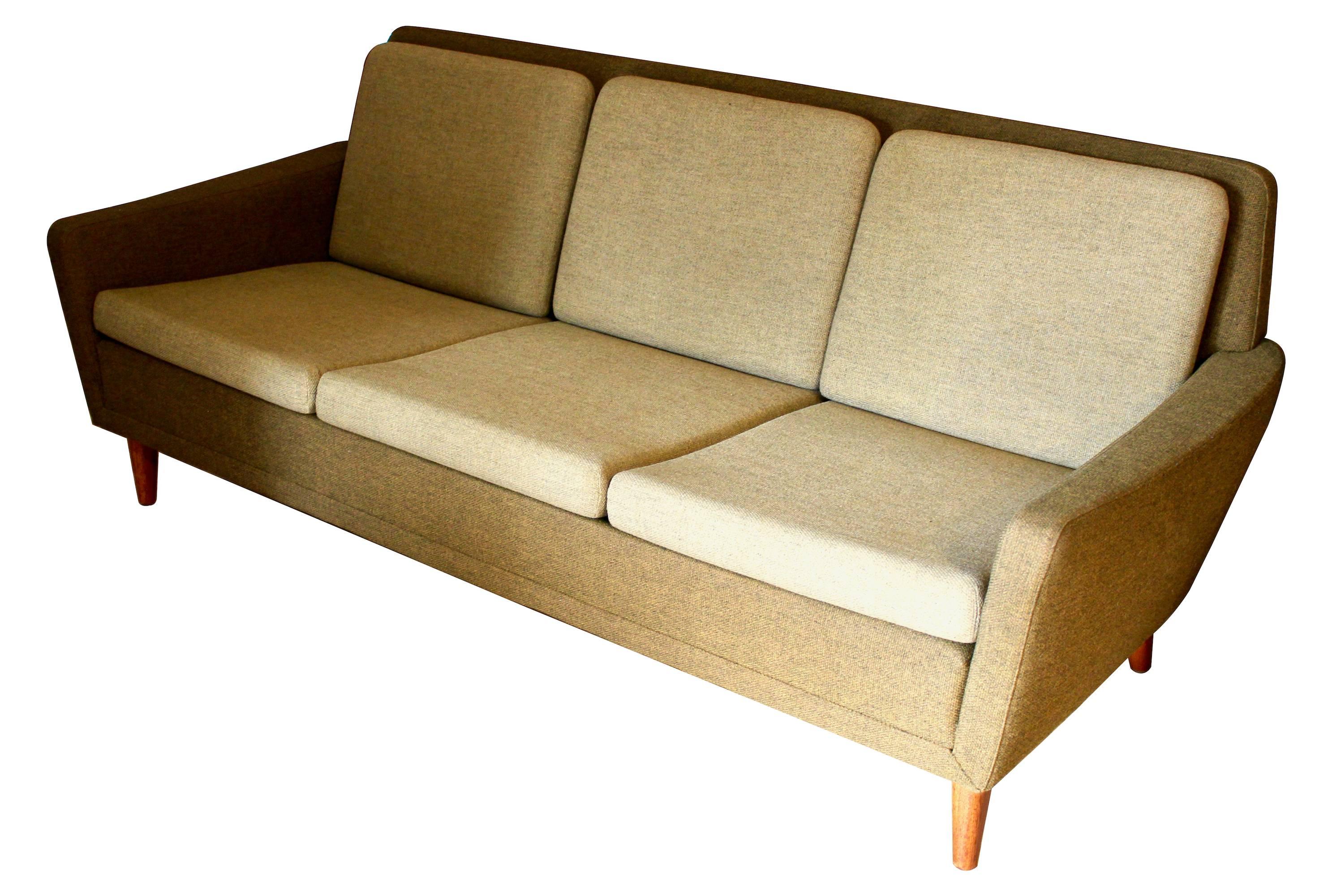 Upholstered sofa by Folke Ohlsson for DUX, circa 1970. The body of the sofa is upholstered in a dark green fabric, and the seat and back cushions are in a lighter green, and there are four tapered teak legs. In excellent condition with original