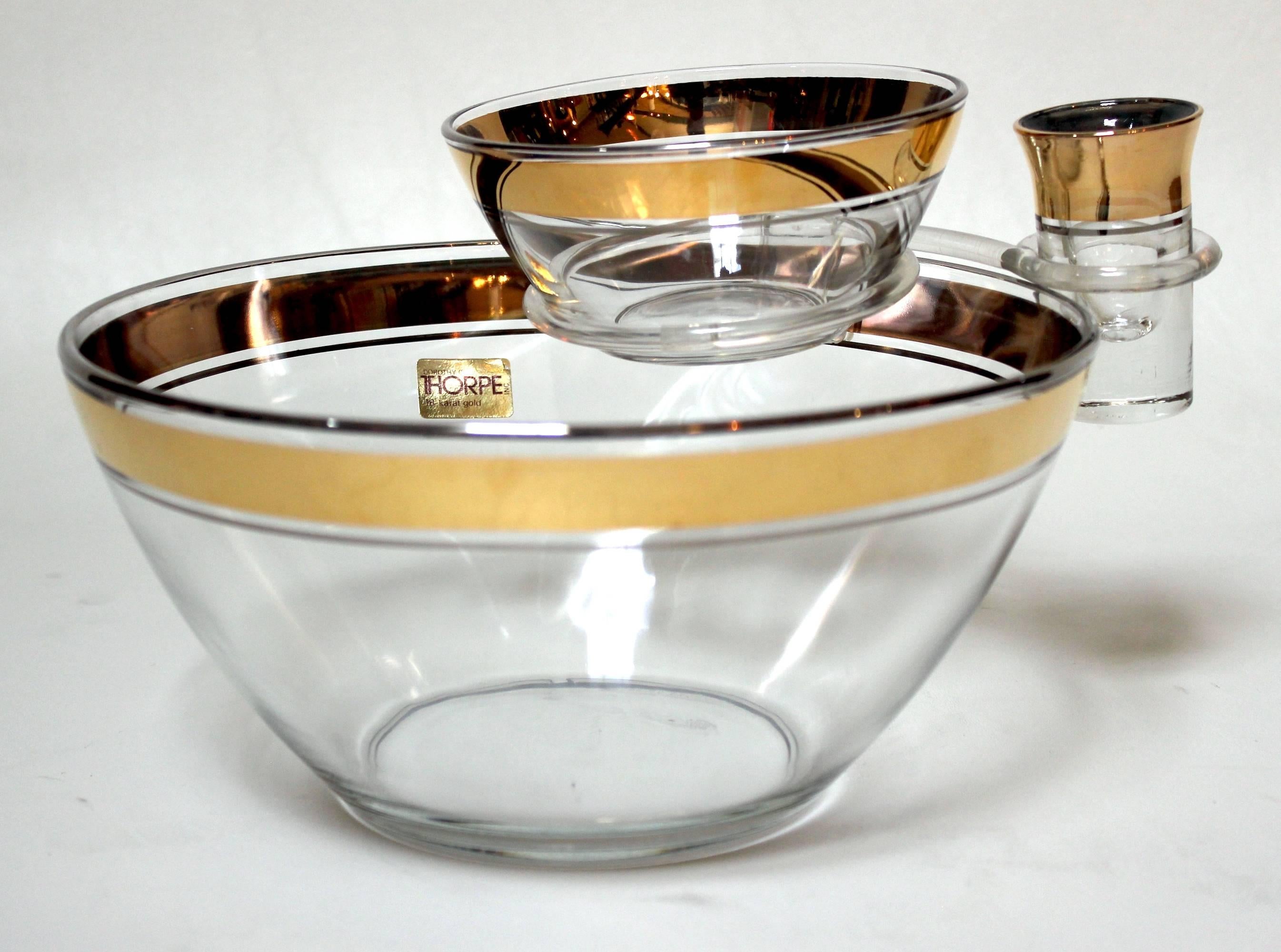 Mid-Century Modern chip and dip set by Dorothy Thorpe. The bowls are crystal with 18-karat gold edge detail. Set consists of a large bowl, a small bowl, a toothpick holder and an acrylic bowl clip. The large bowl measures 9