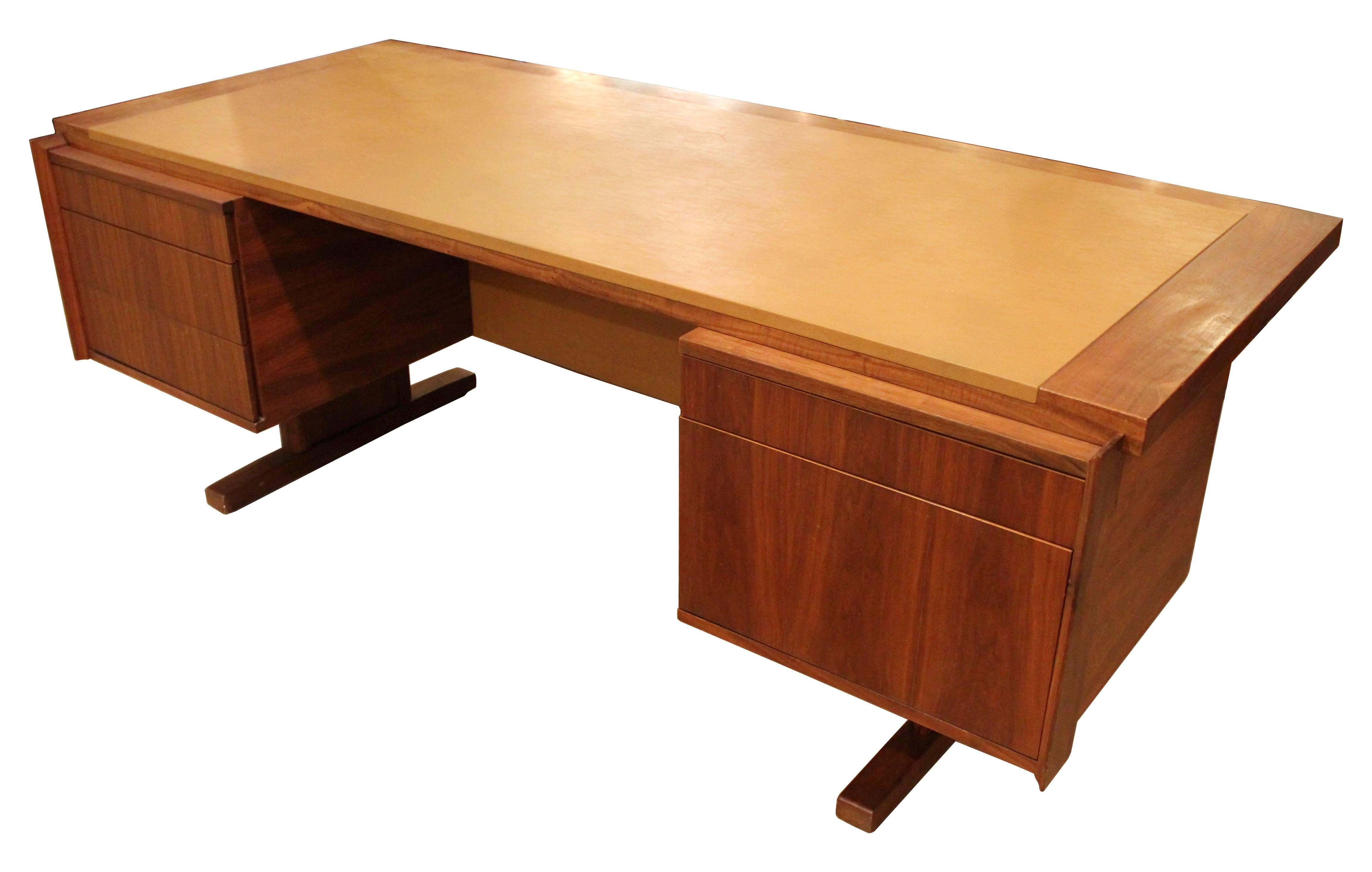1960s walnut executive desk by Martin Borenstein, made in California. The desk has four drawers, one with built-in carved walnut organizer, a file cabinet drawer, and a large leatherette inset desktop. There is slight veneer loss behind one of the