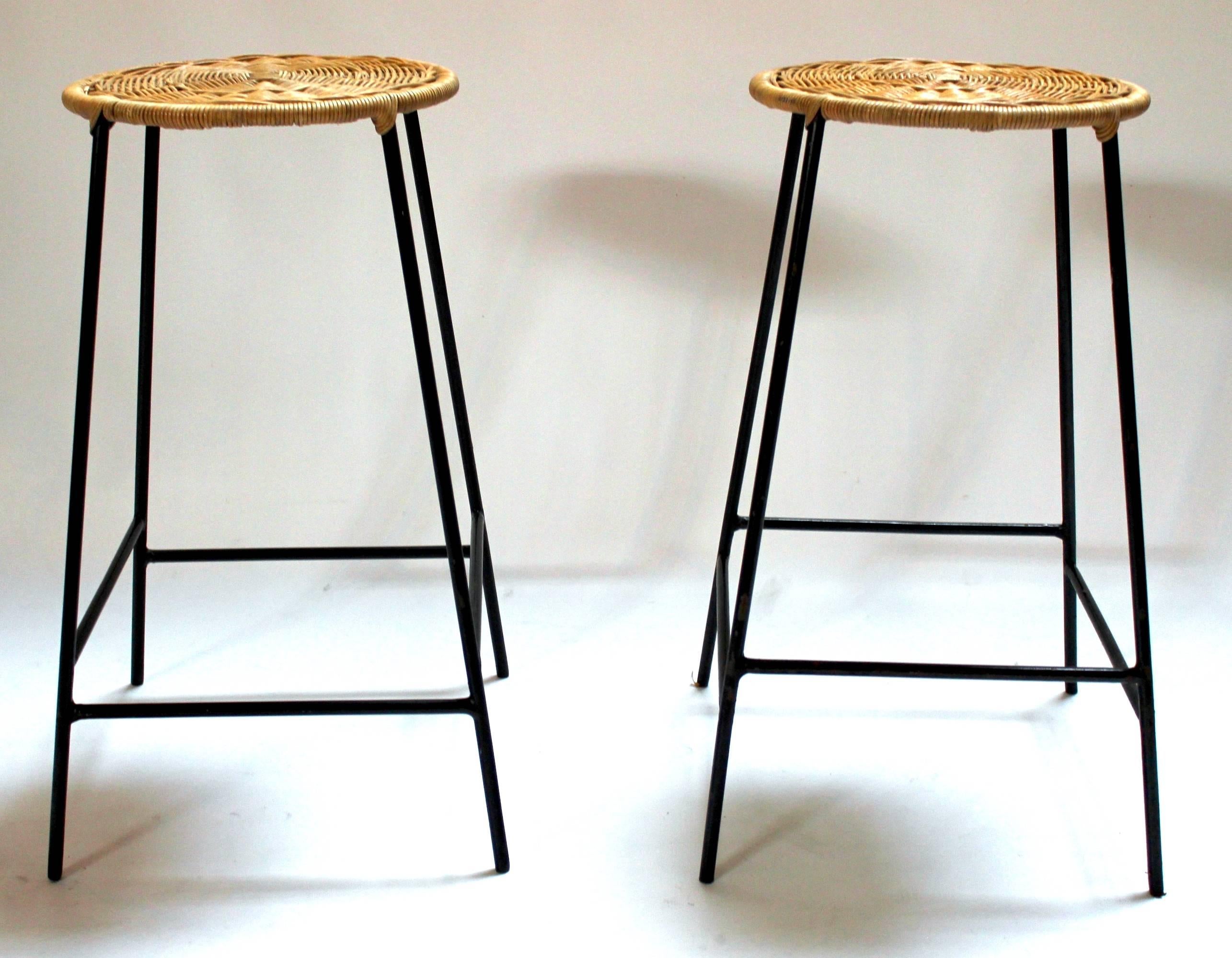 Pair of 1960s metal bar stools with woven wicker seats in the style of Arthur Umanoff. Price is for the pair.