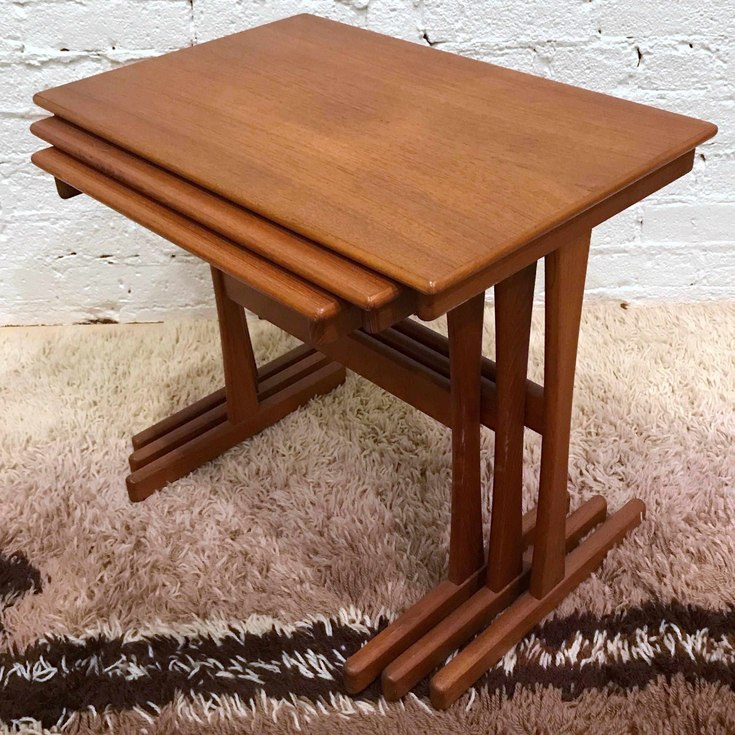 Set of three 1960s Danish modern teak nesting tables designed by Arne Wahl Iversen. The smaller tables slide into grooves in the larger tables, allowing the set to be moved as one unit. 

When nested together, the set measures 21.5