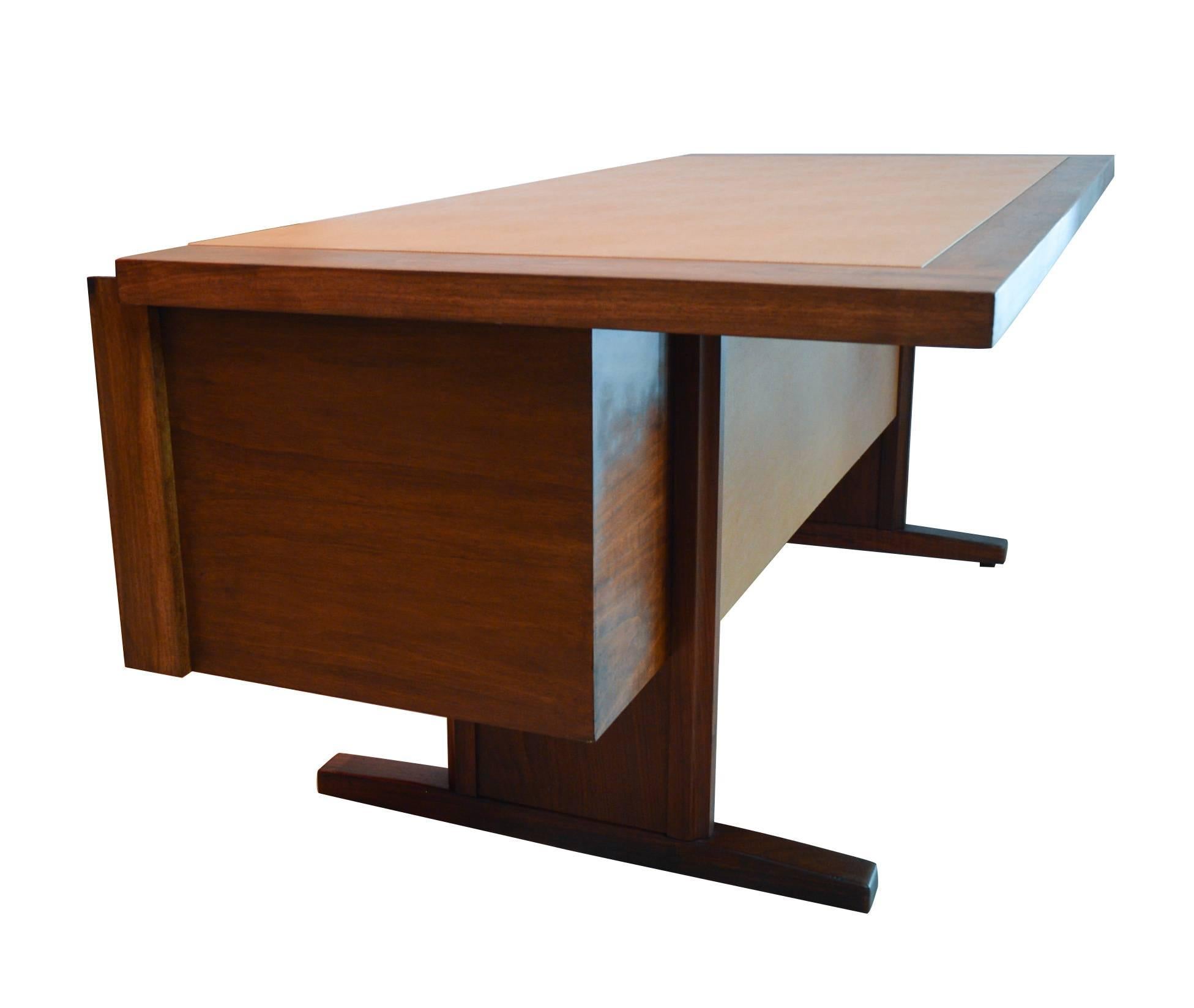 1960s walnut executive desk by Martin Borenstein, made in California. The desk has three drawers, a file cabinet drawer with rails, and a large leatherette inset desktop. There are a few small nicks and discolorations to the leatherette, as shown in
