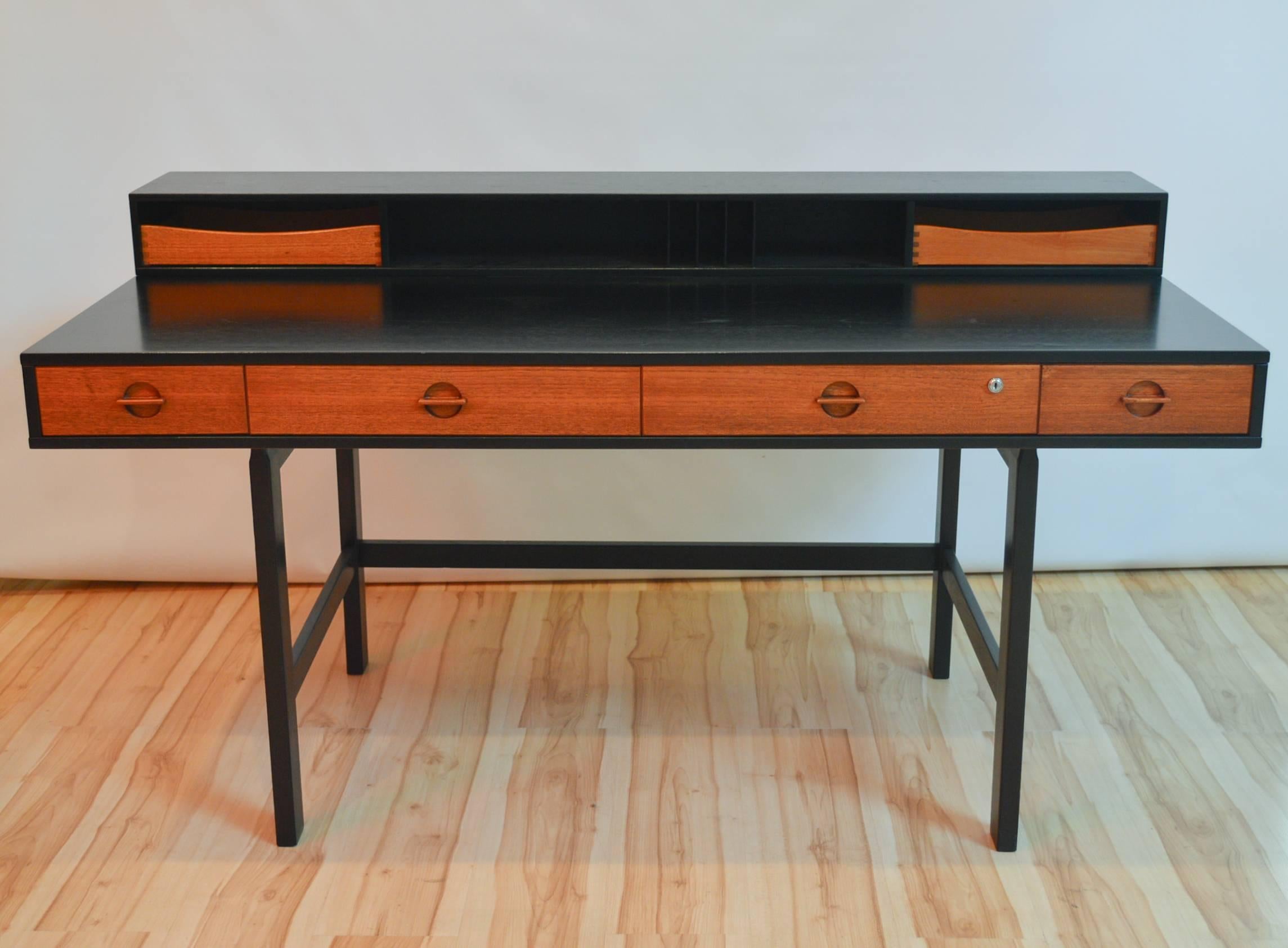 1960s Danish Modern teak flip-top partner's desk designed by Jens Quistgaard for Lovig. The secretary shelf flips down to create a larger workspace. This piece has been professionally refinished and refurbished - the body of the desk has been