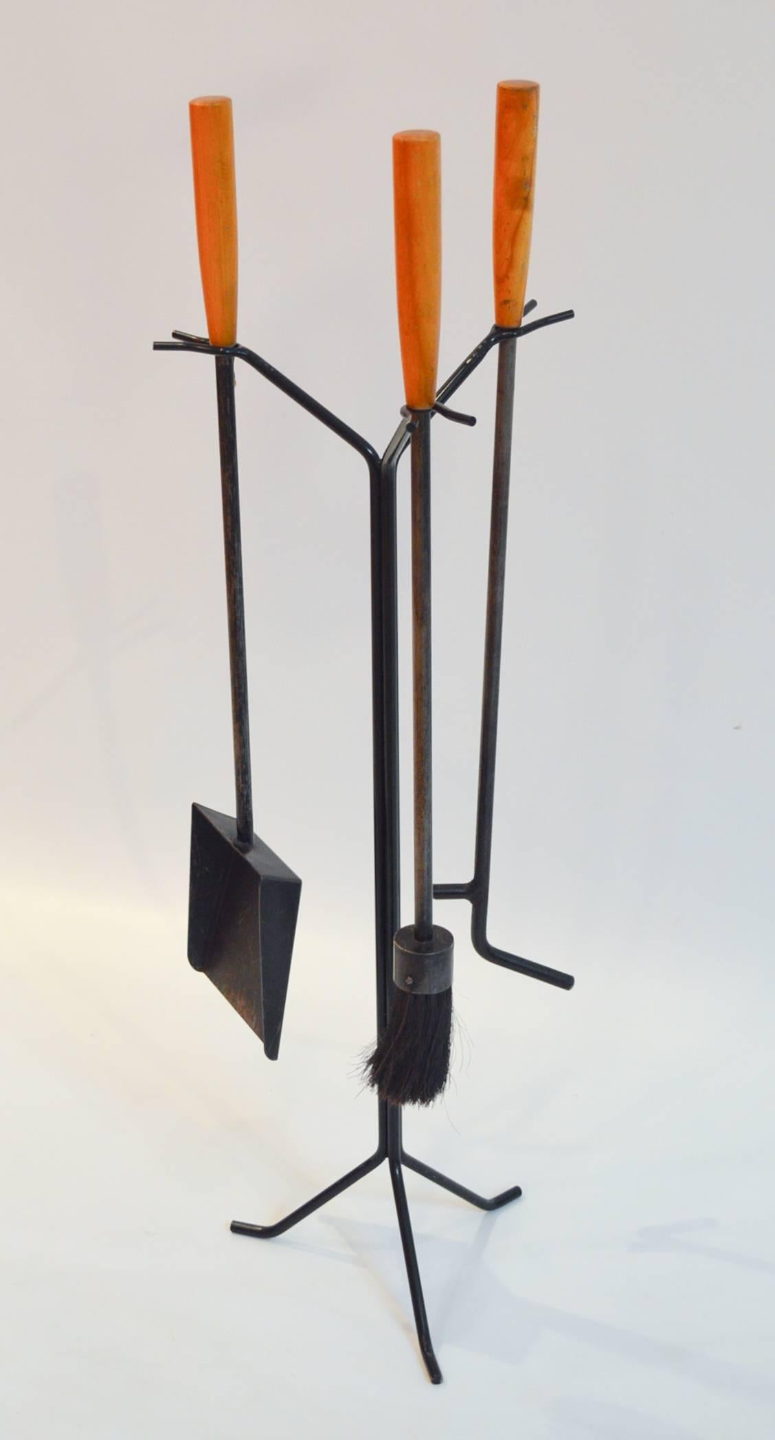 Mid-century modern set of enameled steel and birch fireplace tools designed by George Nelson. The set is comprised of a poker, shovel, and brush; the stand is new and made to the original's measurements and specifications. Price is for the set.