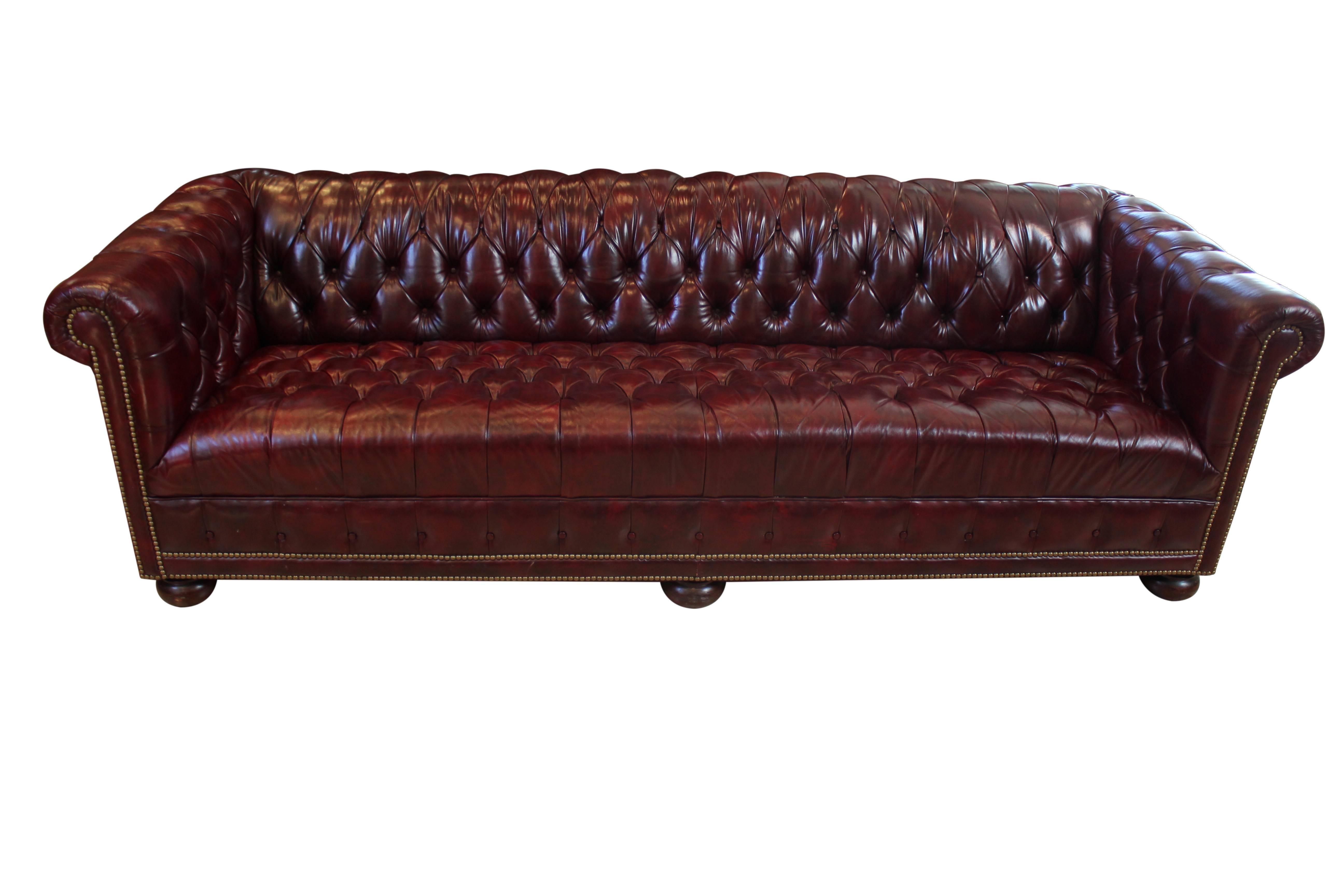 Vintage tufted leather 8' Chesterfield sofa. Oxblood leather with wooden bun feet; in excellent condition with very little wear, and no missing buttons or nail heads. The sofa is unusually long for a Chesterfield, and seats 3-4 comfortably.