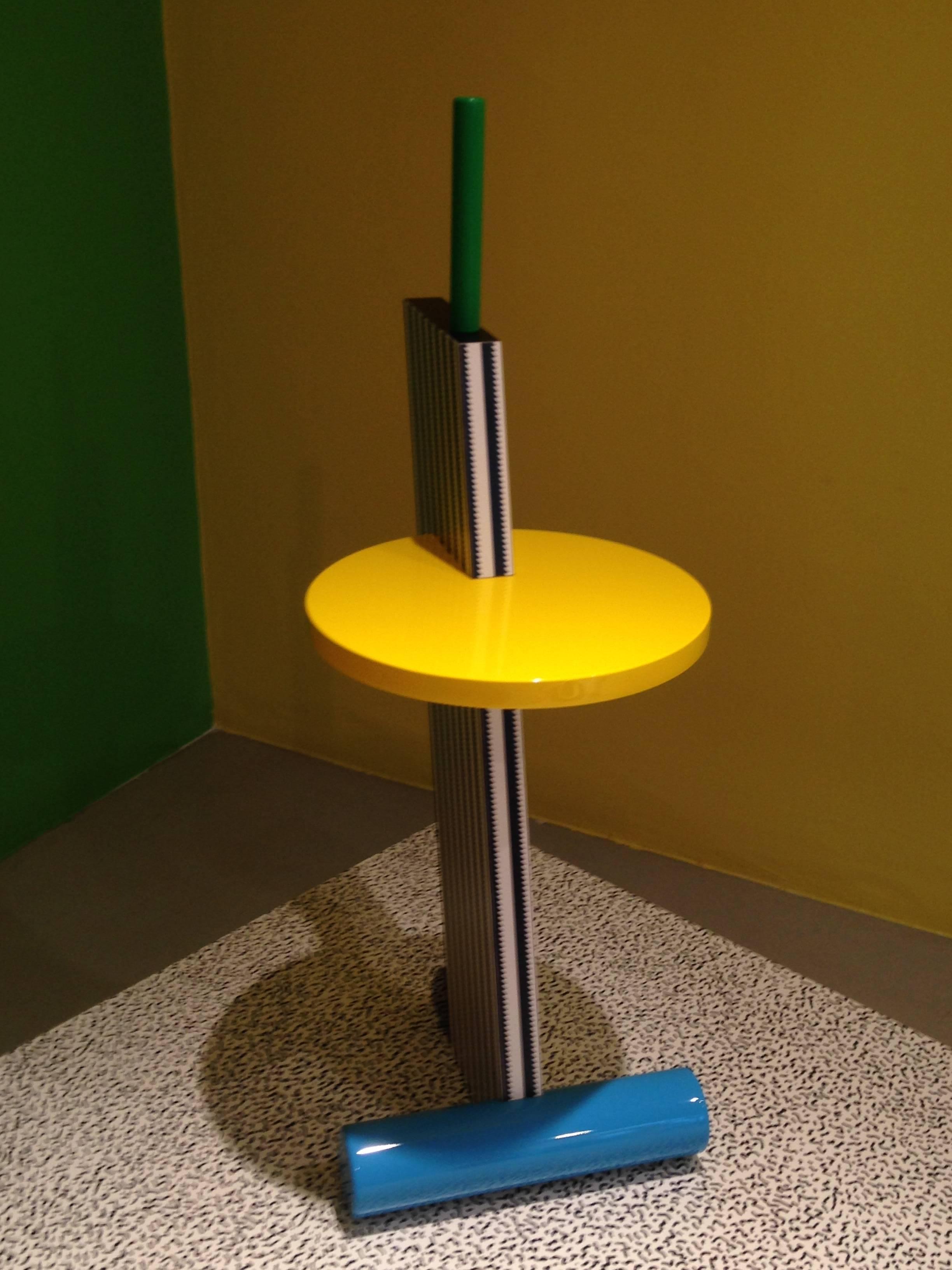 Michele de Lucchi fue miembro principal de los grupos radicales italianos Alchymia y Memphis.

Esta elegante mesa, creada para Memphis en 1984, forma parte de una serie de cuatro que utilizan elementos, color y decoración de superficie similares.