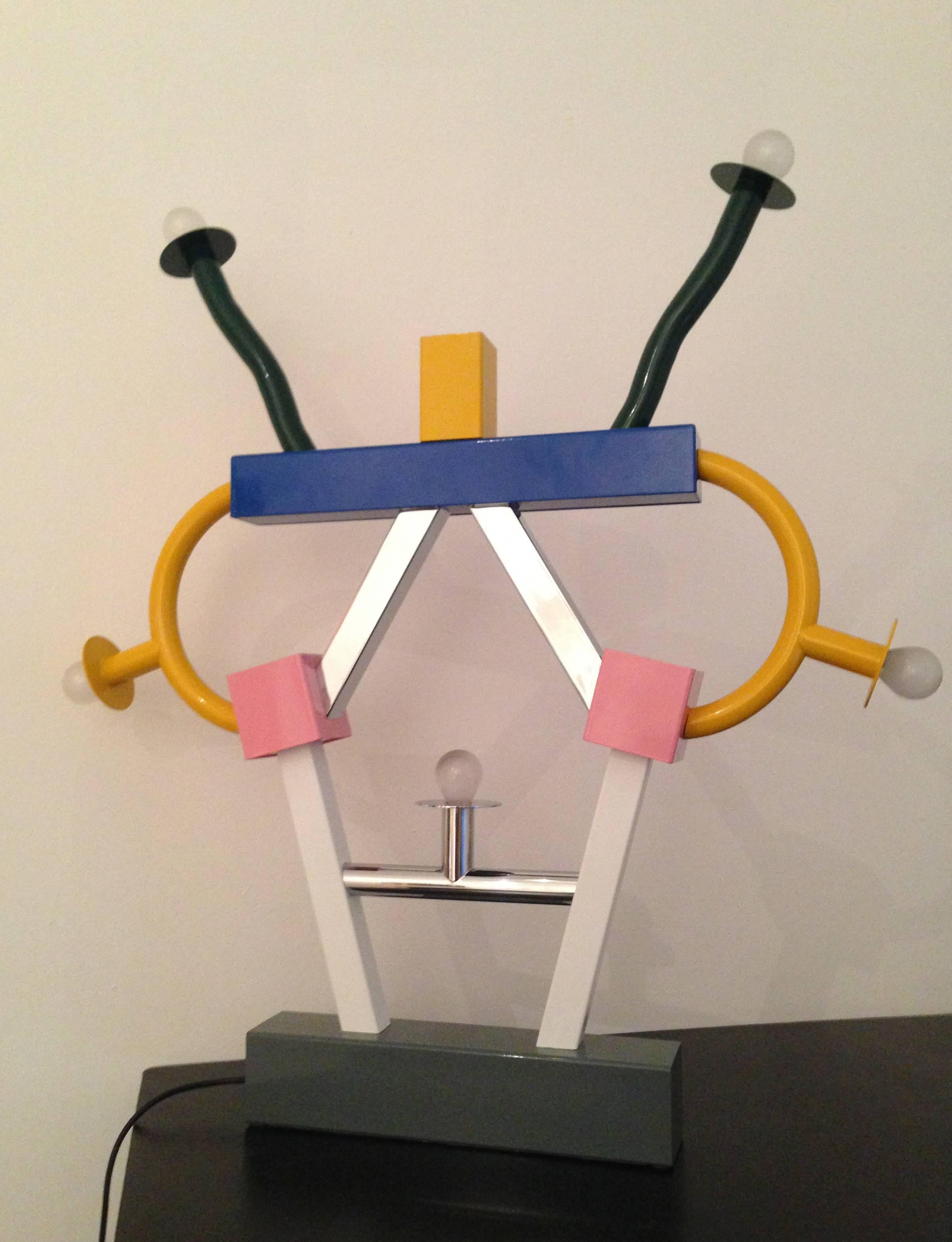 Die Ashoka-Tischleuchte ist ein frühes Meisterwerk von Ettore Sottsass für die 1981 eingeführte MEMPHIS-Kollektion - eine ikonoklastische Leuchte/Skulptur, wie Sie sie nirgendwo anders finden werden!
Mit verschiedenen Lichtquellen, die überall