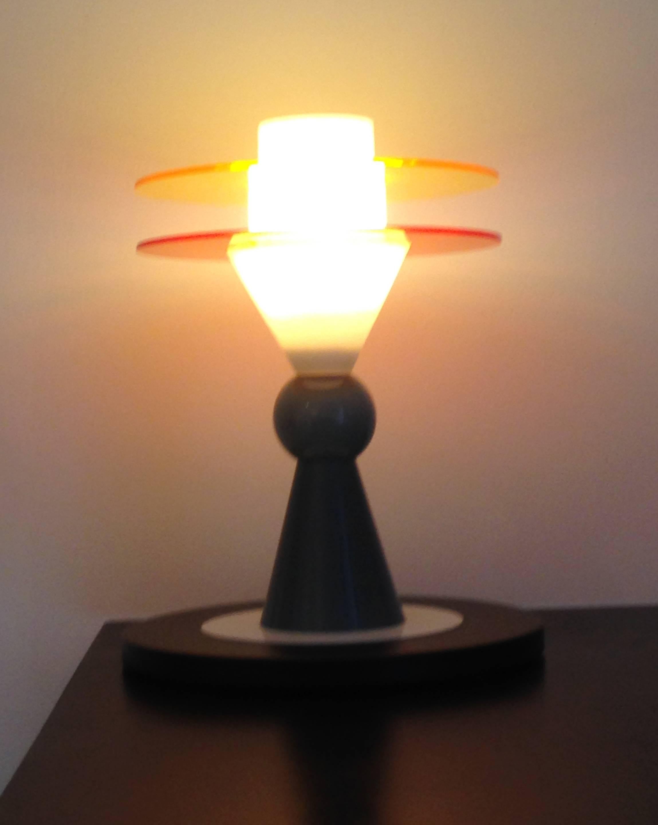 La lampe de table Bay est un chef-d'œuvre époustouflant d'Ettore Sottsass pour Memphis (1983). Fabriquée à partir de couches de plastique perspex coloré et de verre de cristal coloré et blanchi, cette œuvre illumine non seulement l'espace qu'elle