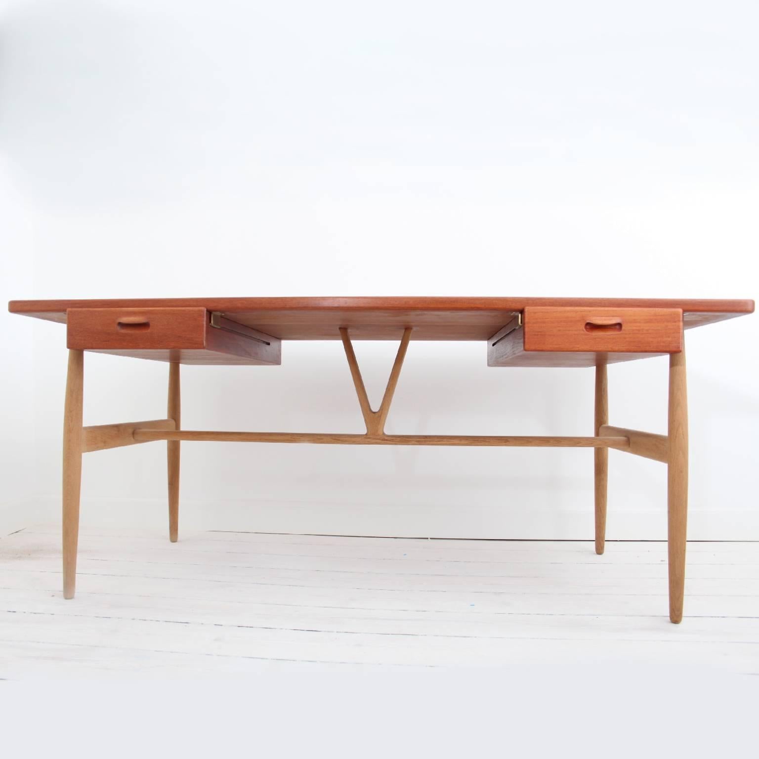 A rare JH563 / V' desk designed by Hans J. Wegner, 1950.

A large writing desk of teak with two hand-carved floating drawers on a base of turned oak legs braced by a hand-carved central wishbone-shaped strut. 

Executed by cabinetmaker Johannes