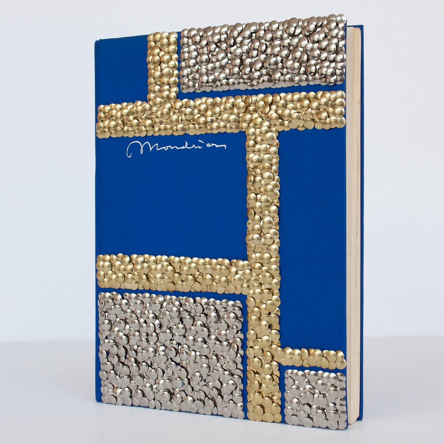 Hand gilded copy of a Mondrian art book with silver and brass thumbtacks forming a geometric grid pattern reminiscent of the iconic artwork by Piet Mondrian on the front cover by Chicago artist Brian Stanziale.

Sculptural and playful,