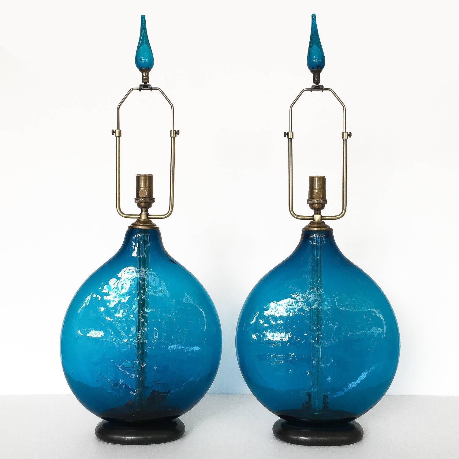 Pair of beautiful and vibrant dark cerulean blue blown glass table lamps by Wayne Husted for Blenko, circa 1960s. Textured or bubbled flask shaped glass bodies with matching original glass finials. Ebonized solid wood bases. Newly wired with antique