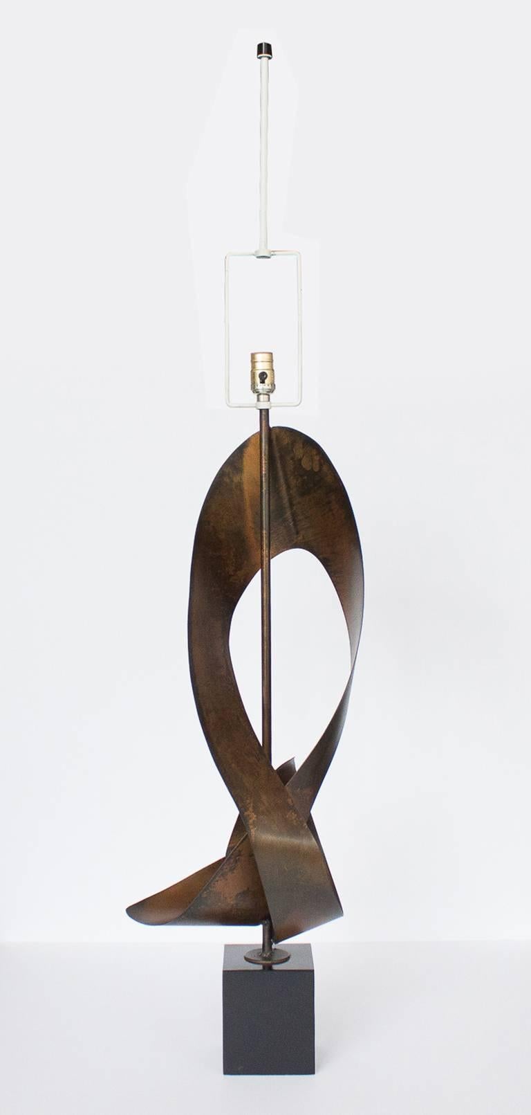 Modern and sculptural table lamp, produced circa 1960s by Brutalist artist Harry Balmer for Laurel Lamp Company. The lamp features a bronze / copper tone patinated steel sheet, reformed and soldered into a curved, abstracted ribbon shape,