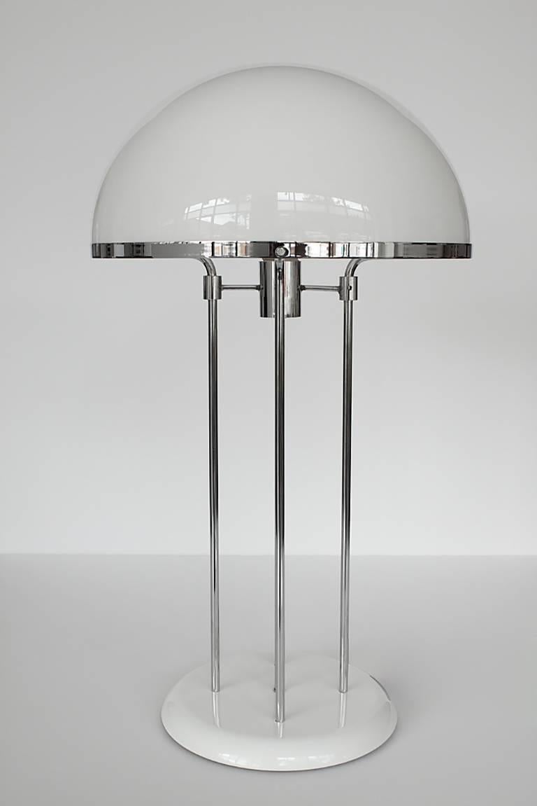 This 1970s table lamp features 5 chrome supports, white enameled weighted base and white acrylic dome shade. Shade sits within chrome ring.  In-line switch. Takes one standard base light bulb.  Excellent vintage condition with no damage to shade or