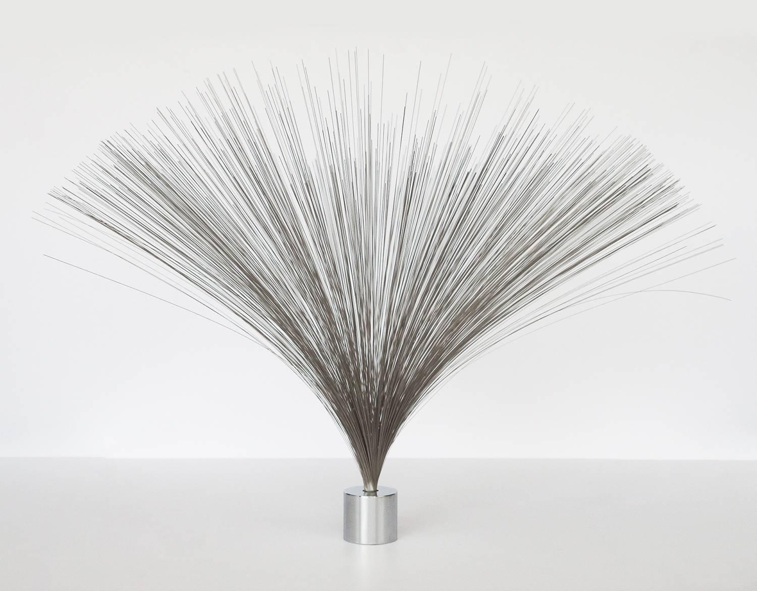 Inspired by the form made famous by Harry Bertoia, this spray-shaped Kinetic sculpture is made of hundreds of Fine steel wires gathered within a heavy chrome plated steel cylinder base. The piece is marked with a label on the bottom of the base. A