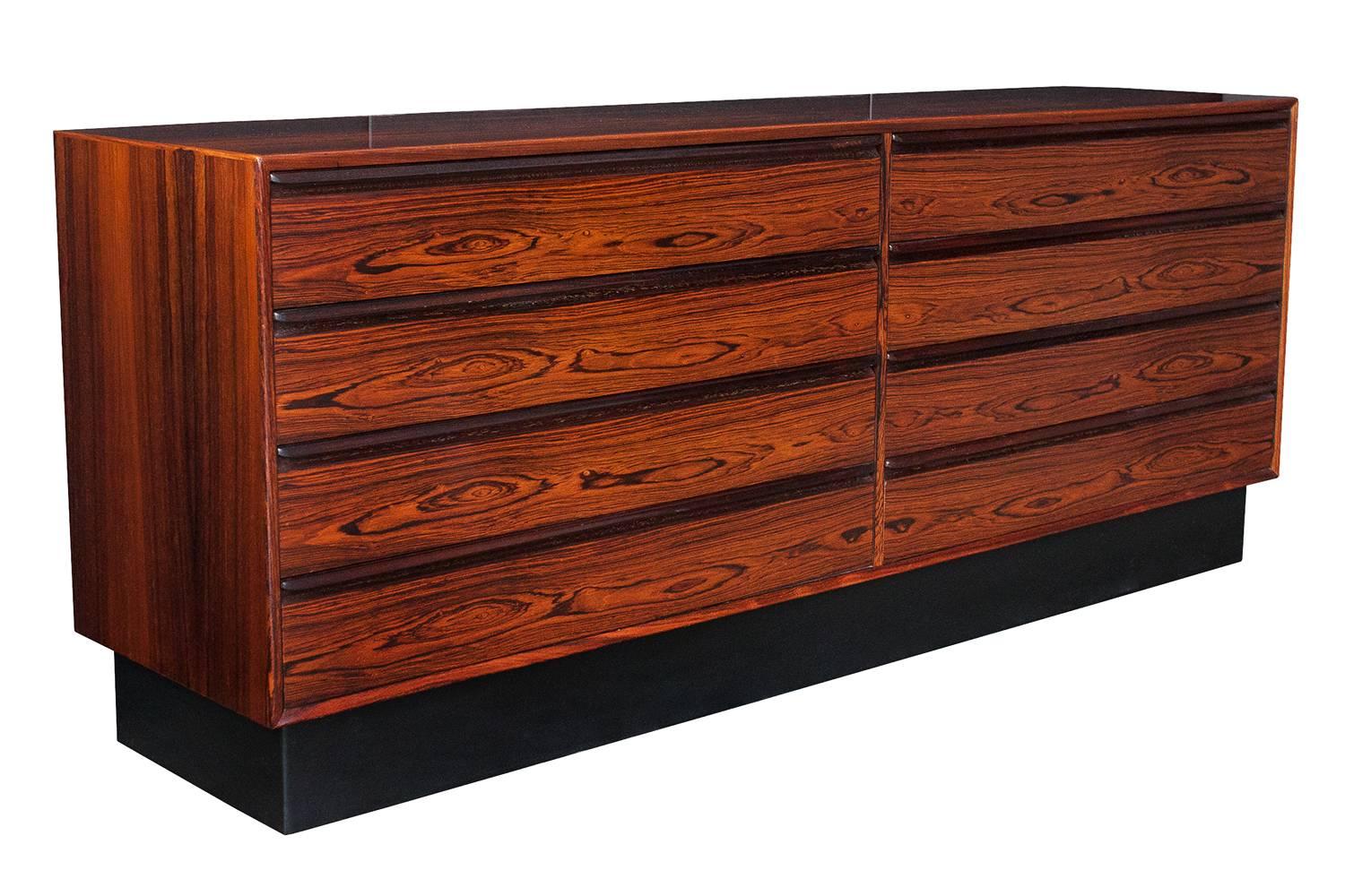 A Brazilian rosewood eight-drawer chest by Westnofa of Norway. Figured rosewood veneer with solid rosewood molded handles. Mahogany lined drawers. Original black Naugahyde faux leather plinth base. Retains Westnofa label on the back of the