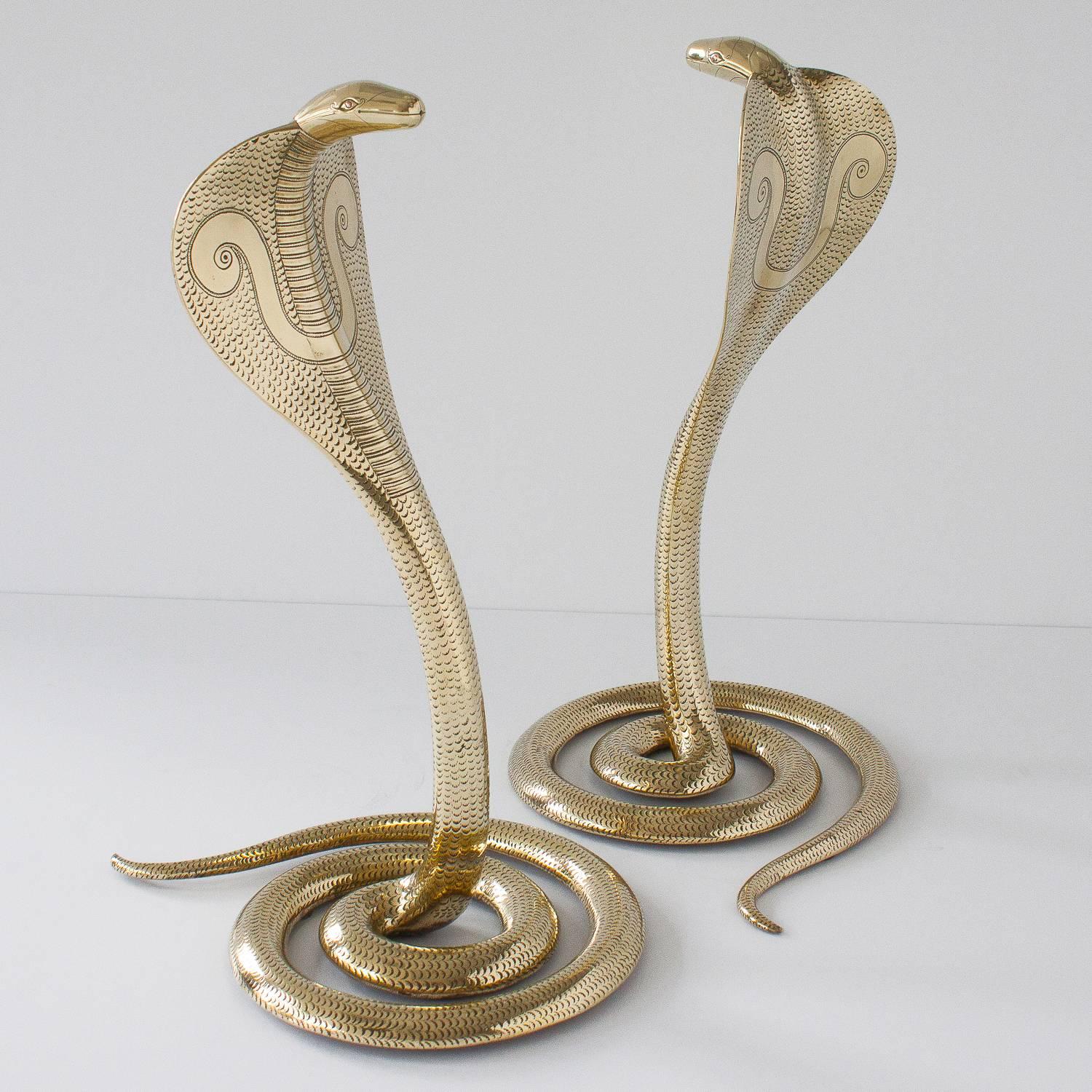 Incredible and dramatic pair of large solid brass cobra snake sculptures. Consider using as decorative andirons or table top sculptures. Handcrafted standing cobras in polished brass with carved and hammered details. Fully decorated. Opposing coiled