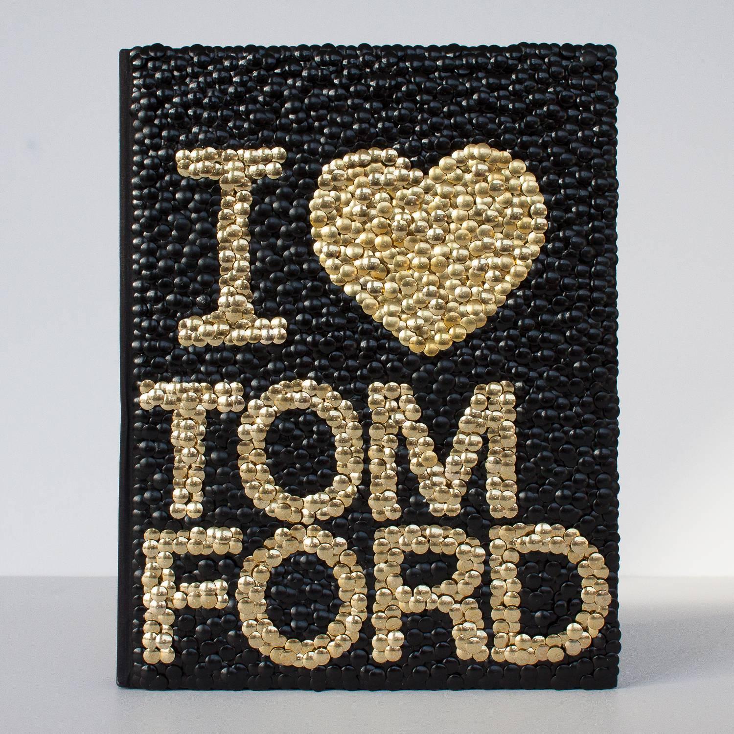Hand gilded copy of a Tom Ford fashion book with brass and hand-painted black thumbtacks forming the phrase I 