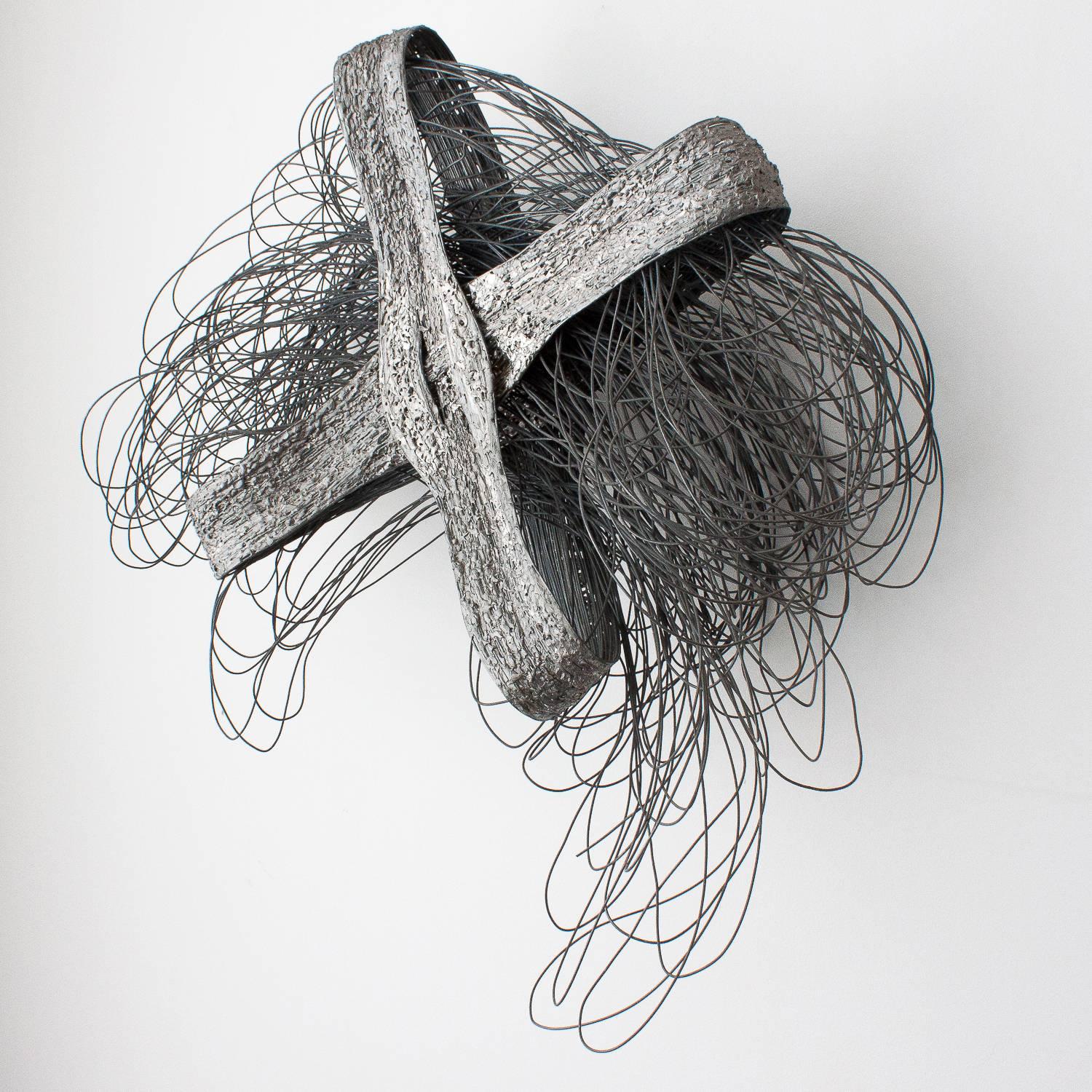 Brutalist wire wall sculpture by Detroit artist J Yam, circa 1970s. Unique abstract form. A looped nest of hand-sculpted matte grey wire is contained within two crossed ribbon like loops. The 2.5" wide flat loops are created by fused wire with