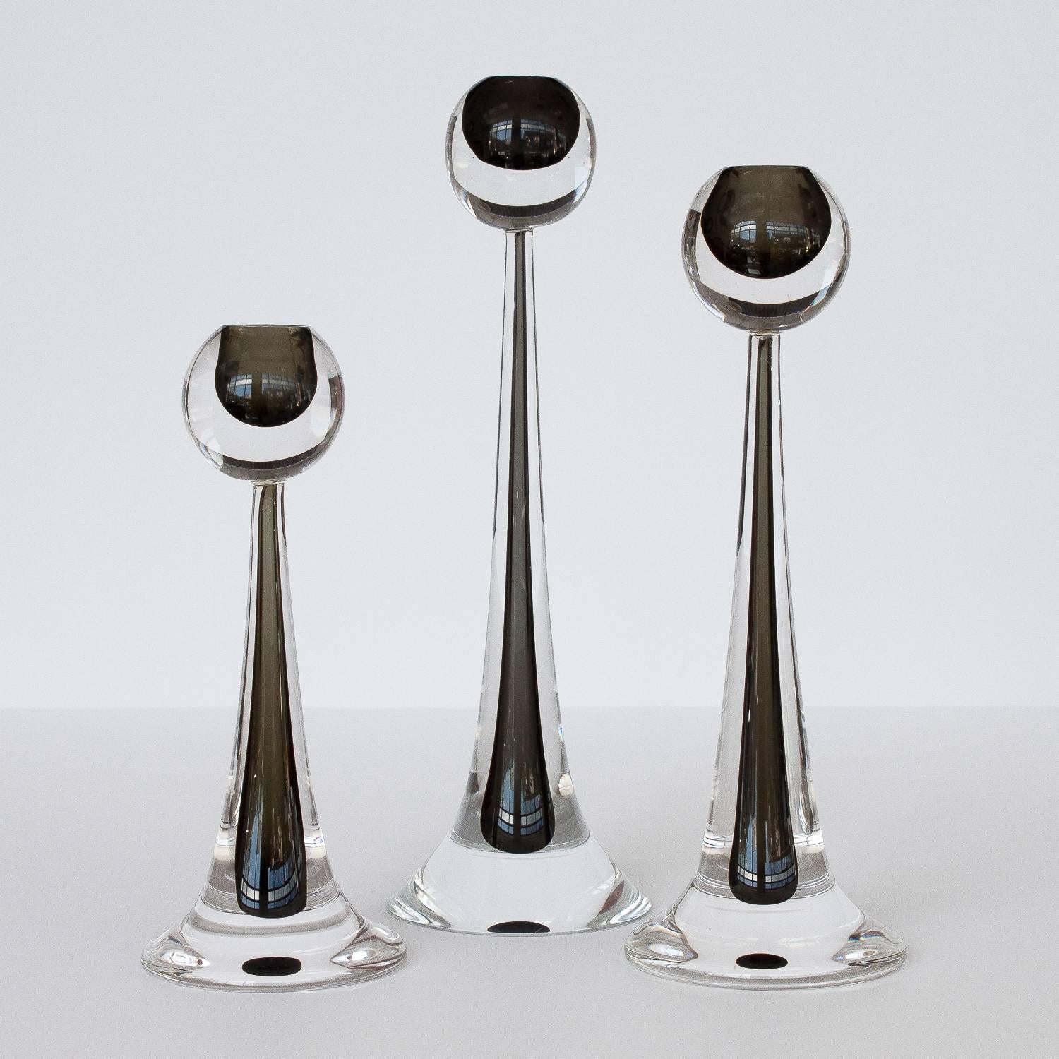 Set of three stunning Modernist handblown Murano glass candlesticks by Cenedese. These candlesticks feature a tapered teardrop design made of handblown Murano glass. Each candlesticks features a spherical topper that is accentuated with an interior