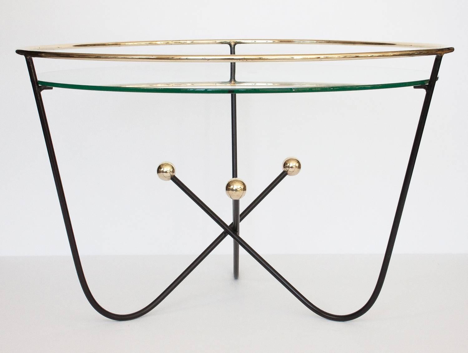 1950s Jean Royère style, black enamel and brass cocktail or side table by Edward Ihnatowicz for Mars Furniture. Elevated solid brass gallery rail above the 24.5" inset glass top. Three black enameled wire legs curve down, gather and cross at