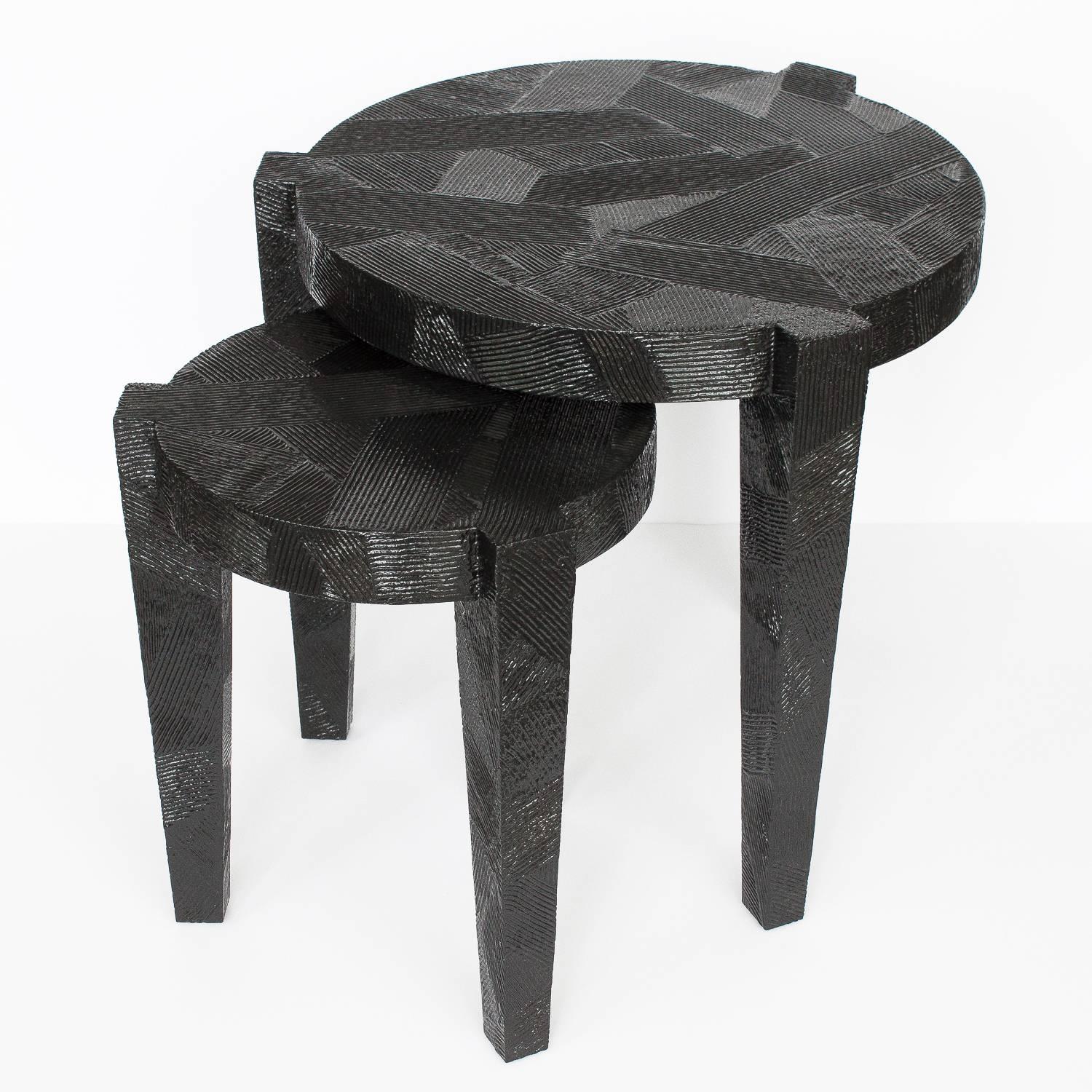 Set of two black lacquered raked textured nesting side tables. Three legged design. Tapered square legs protrude from the round table surface. 2.25