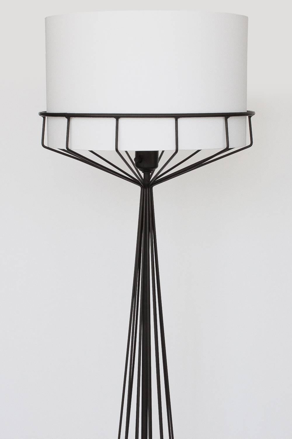 Black wire frame floor lamp designed by Tony Paul from the wire series, circa 1950s. Striking hourglass shape that opens up to cradle the round shade. The shade has been replaced with a white cotton 10" H x 16" DIA cylinder shade and is