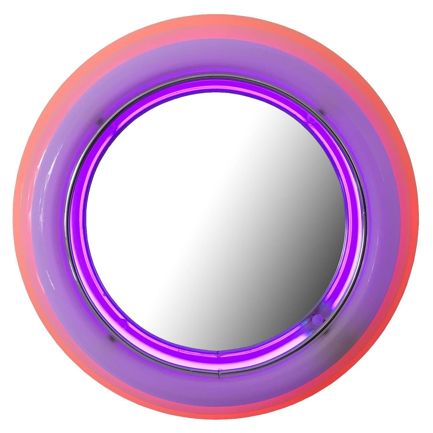 Sottsass style round sculptural acrylic wall mirror with neon lights. off-white molded stepped acrylic form with two internal rings of neon in purple and pink. Recessed round mirror. Clear acrylic face framed in chrome banding. Similar in style to