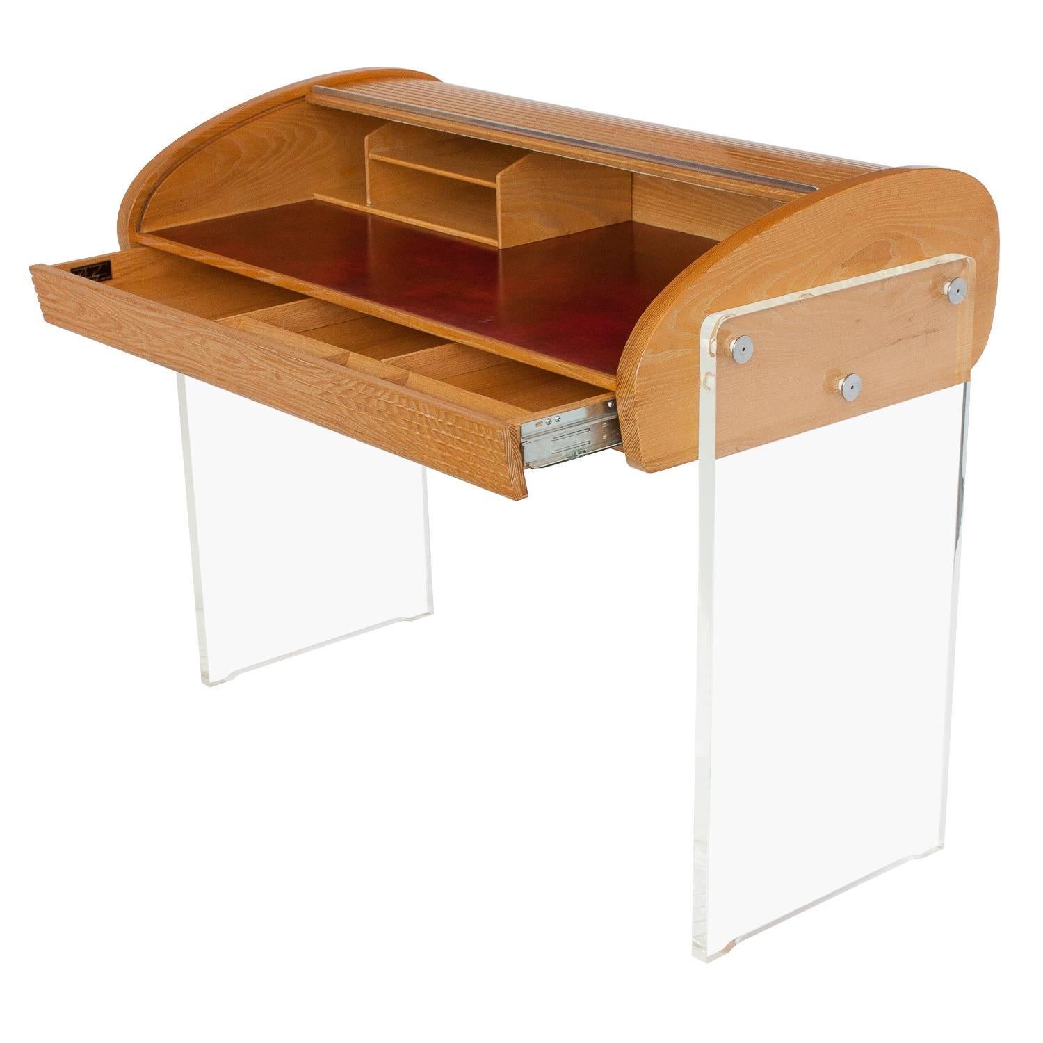 Vladimir Kagan roll-top writing desk, model P 902. 

A roll-top writing desk in oak with Lucite legs and leather writing surface. The desk features a tambour roll top concealing a red leather writing surface and letter organizer. One integrated