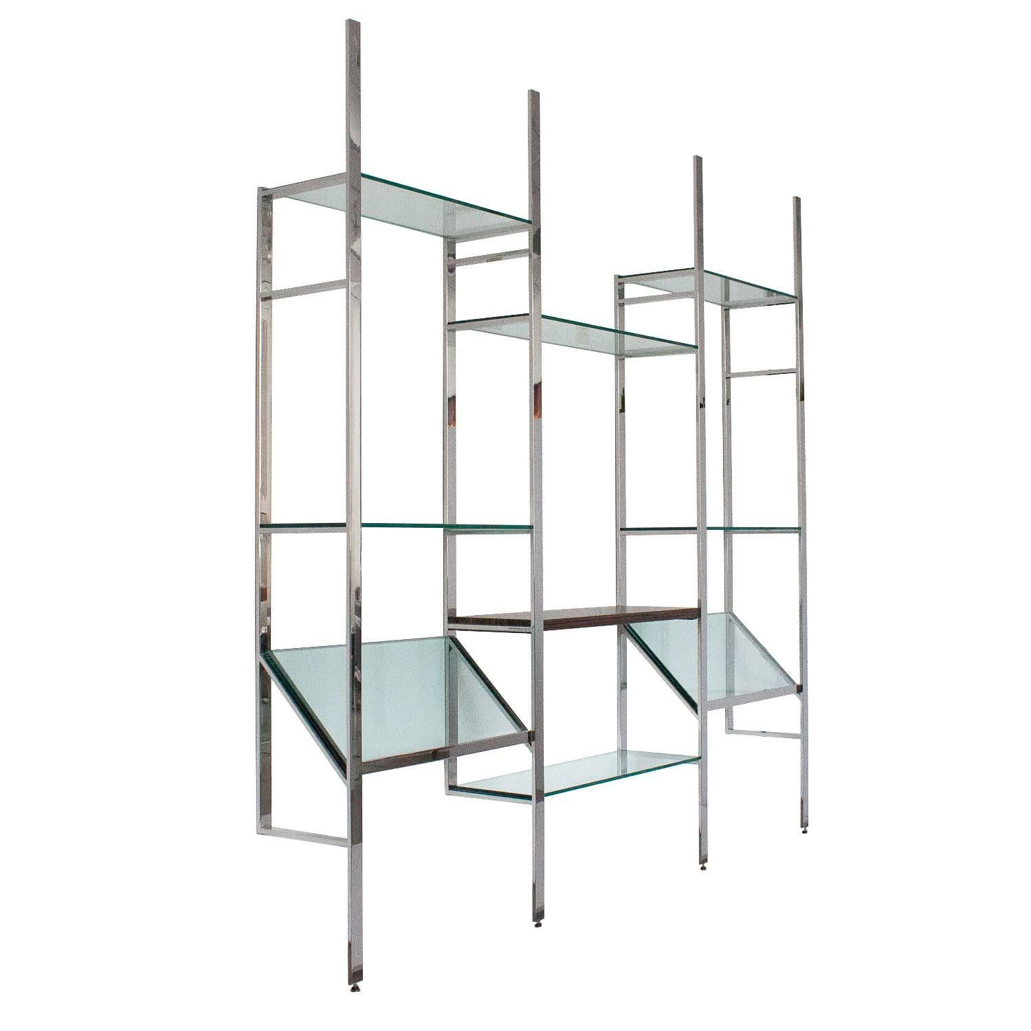 Wall-mounted shelving system by Milo Baughman. Four polished chrome-plated 1.5" W steel wall-mounted vertical supports. Six 3/8th inch glass shelves and two angled glass magazine / art display shelves. Macassar ebony wood central shelf.