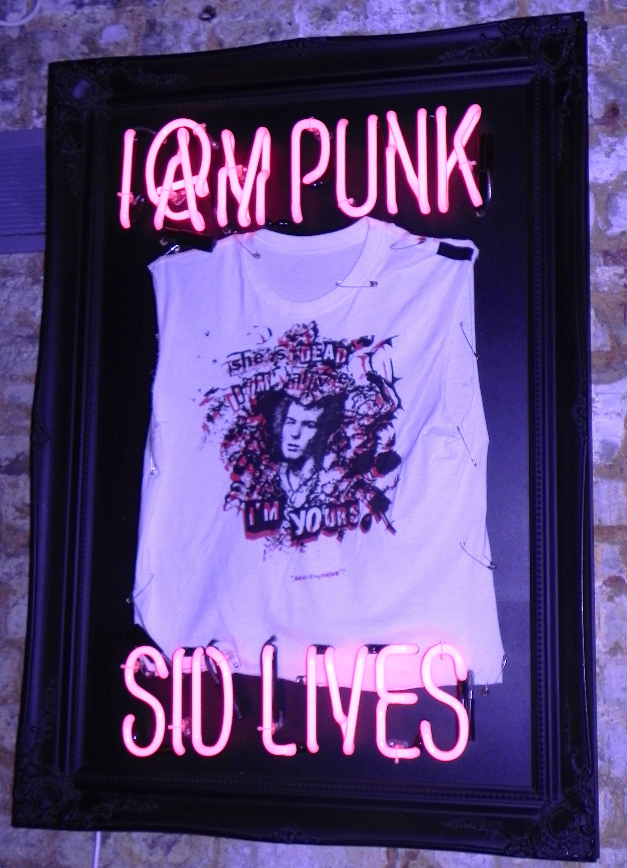 SID LIVES
illuminati neon
Original sex pistols T-shirt in Baroque frame with pink neon.
Measures: 106 x 79 x 12 cm.
£4000.

Inspired by the cultural vibes embedded in London, illuminati neon creates beautiful neon pieces with a hint of punk