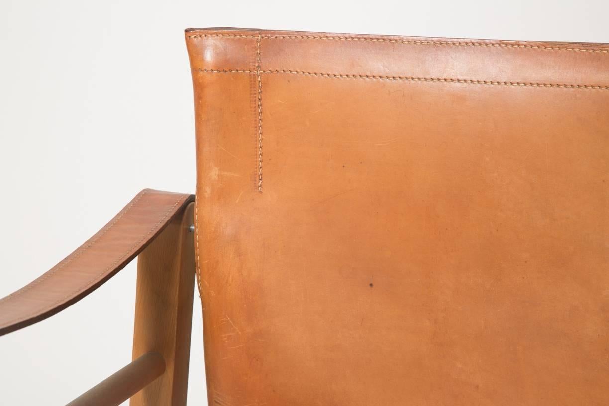 This Model 2221 Safari chair was designed by Børge Mogensen and manufactured in Denmark in the 1950s. It is made from oak with cognac saddle leather upholstery with a light patina. The chair remains in very good vintage condition although the